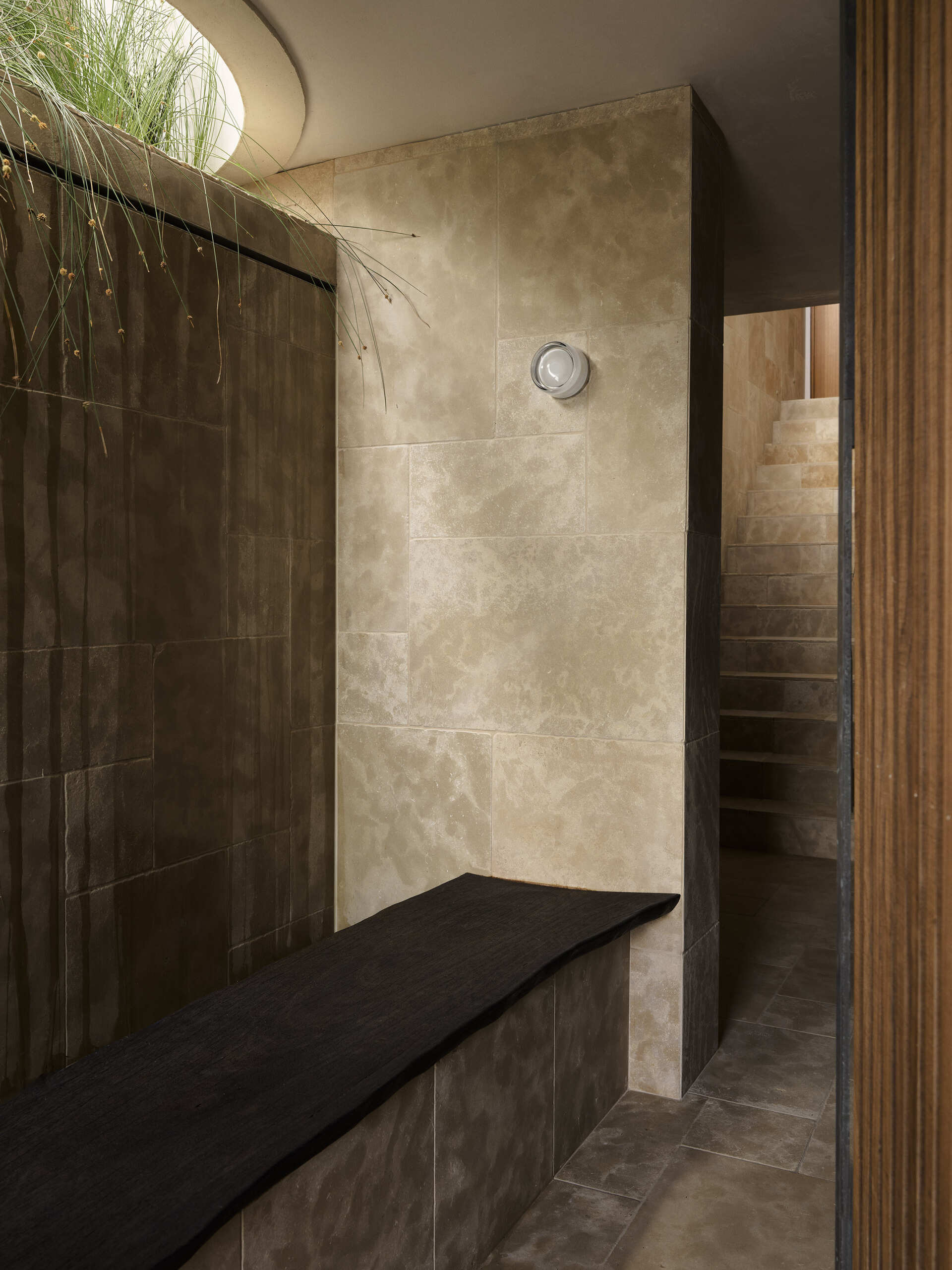 The arrival sequence begins beside the garage, where the architecture transitions into the stepped form of the property. The use of limestone helps tie the lower portion of the home to the rocky landscape, while the elevated gardens bring greenery onto the different levels.