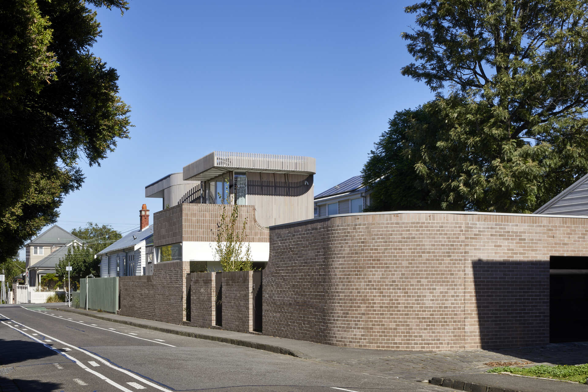 Warm Bowral brick and Blackbutt timber give this sculptural Clifton Hill extension an earthy exterior, while curved walls soften its contemporary form.