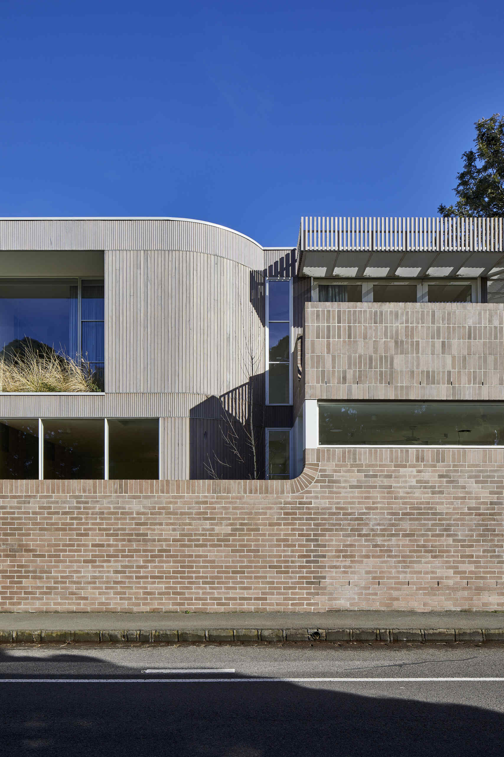 Warm Bowral brick and Blackbutt timber give this sculptural Clifton Hill extension an earthy exterior, while curved walls soften its contemporary form.