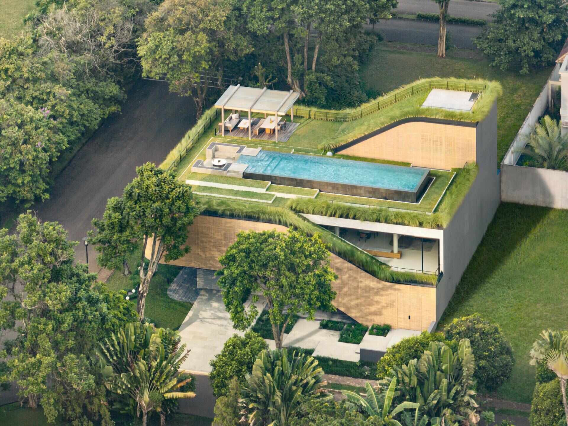 Split Mass Residence in Banten, Indonesia, by K-Thengono Design Studio combines a family home and office across multiple levels, with split volumes, courtyards, outdoor spaces and a rooftop pool.