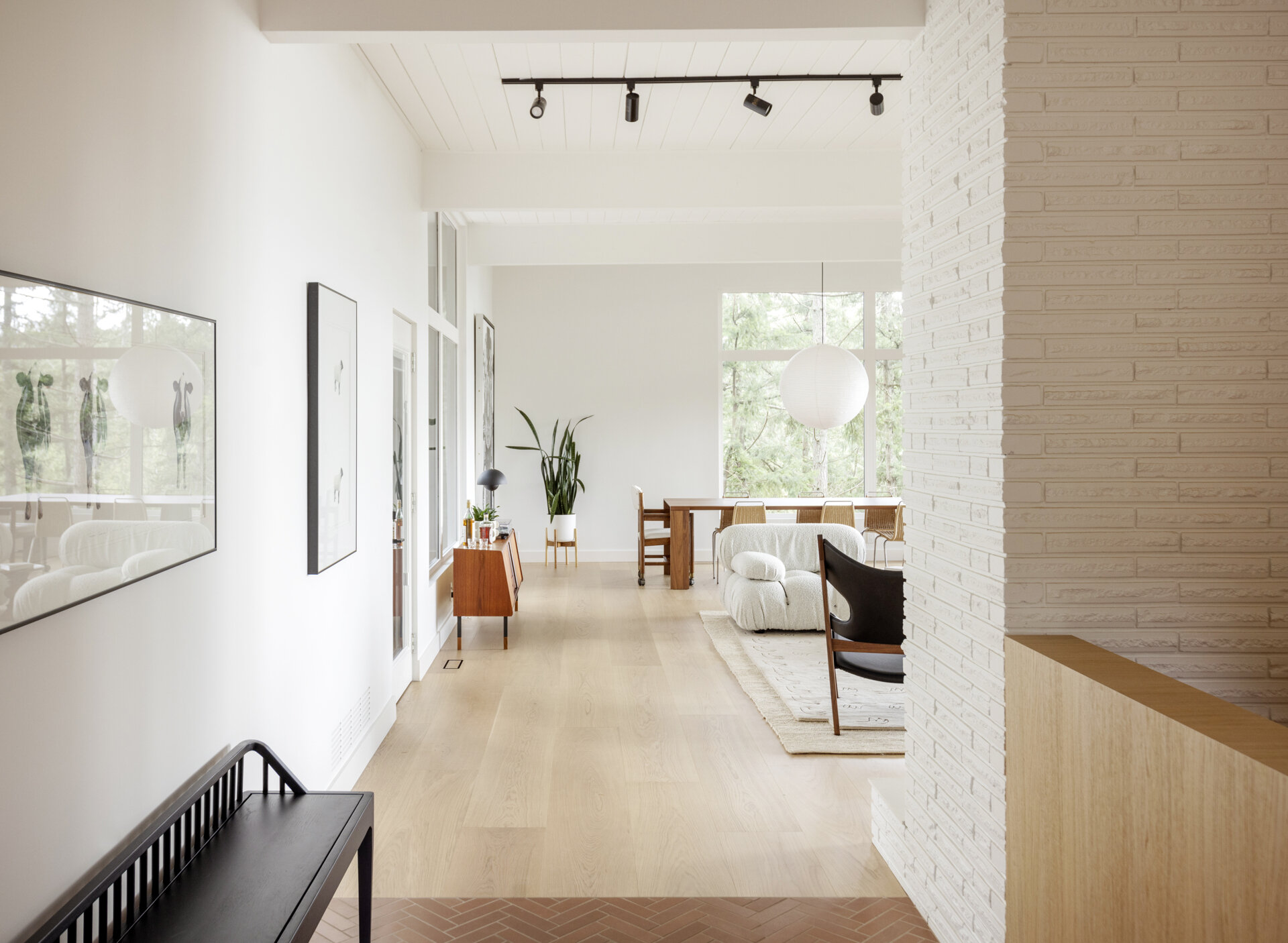 Natural wood panelling, terracotta floor tiles, original brick walls and a post-and-beam ceiling bring warmth and mid-century character to the hallway of this renovated West Vancouver home.
