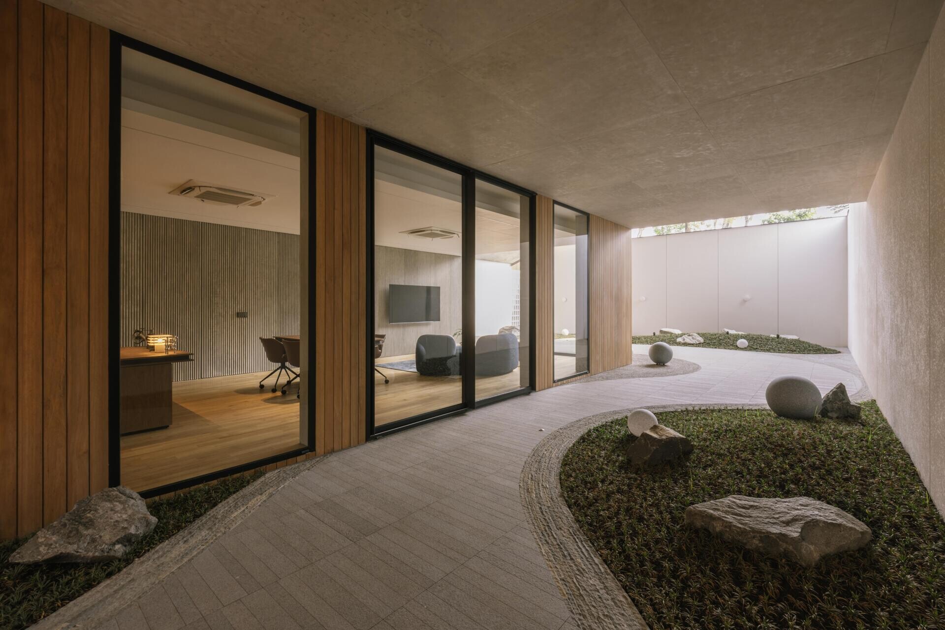 The ground floor of Split Mass Residence combines an office, meeting room, service areas and a garden arcade, creating a separate working zone within the family home.