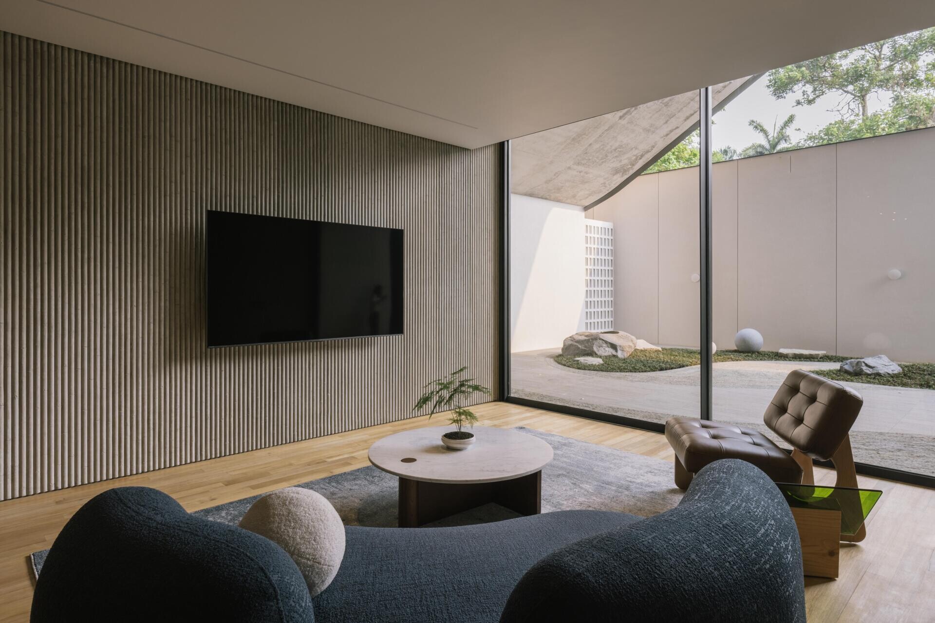 The ground floor of Split Mass Residence combines an office, meeting room, service areas and a garden arcade, creating a separate working zone within the family home.