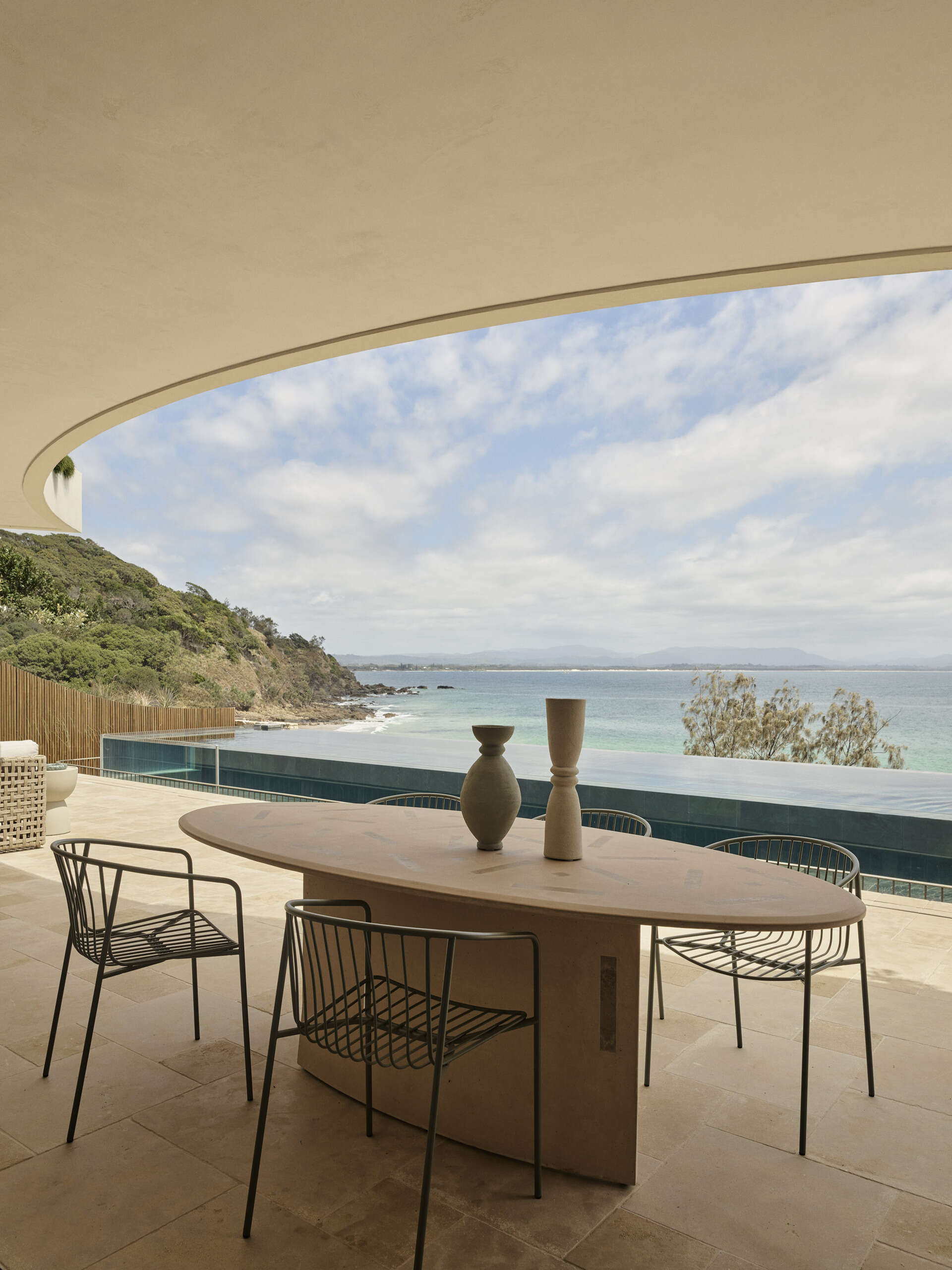 A 20-metre infinity pool sits along the edge of this Byron Bay home, with a Perspex pool edge visually connecting the water to the ocean and an outdoor shower completing the coastal setting.