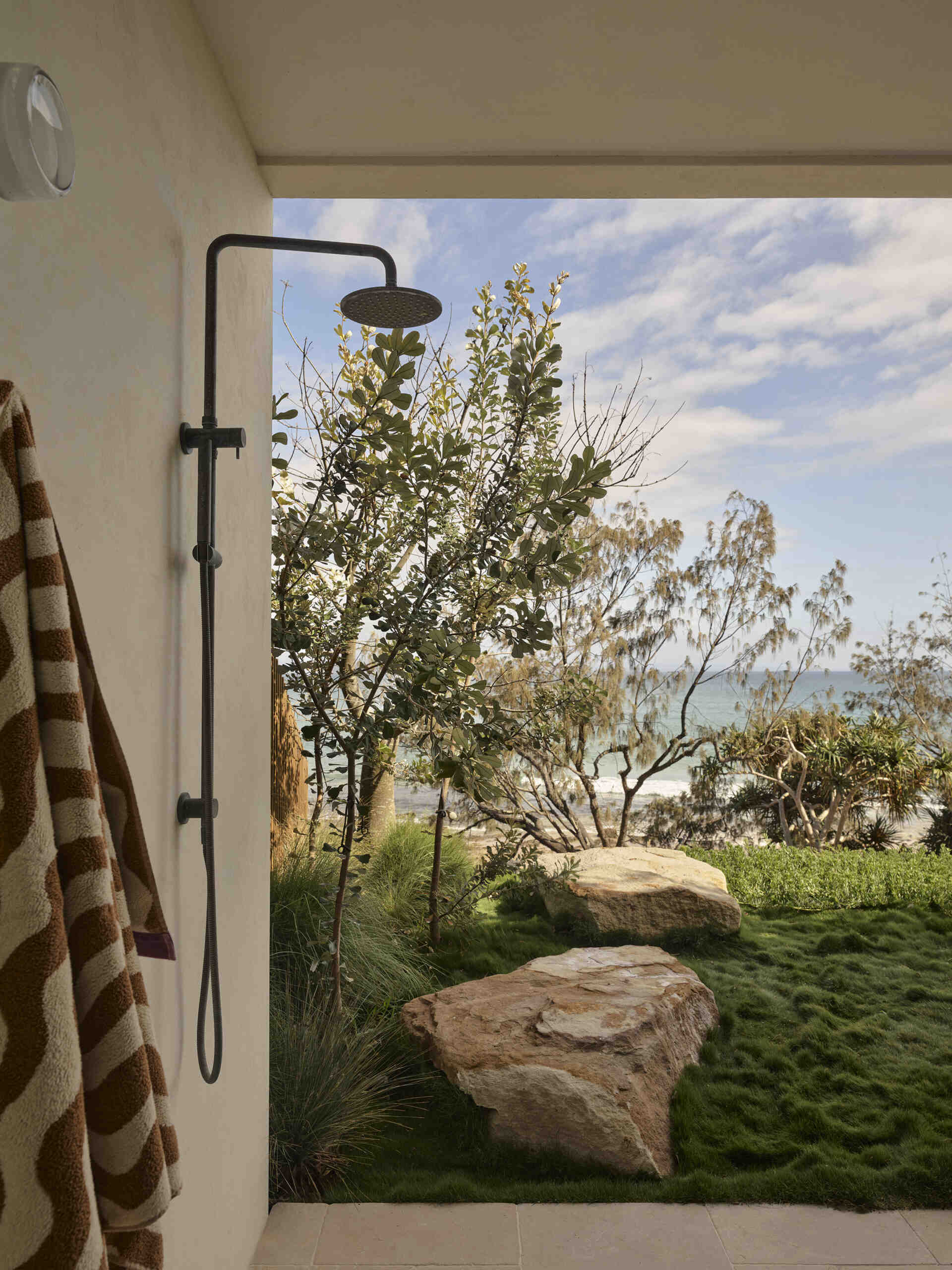 A 20-metre infinity pool sits along the edge of this Byron Bay home, with a Perspex pool edge visually connecting the water to the ocean and an outdoor shower completing the coastal setting.