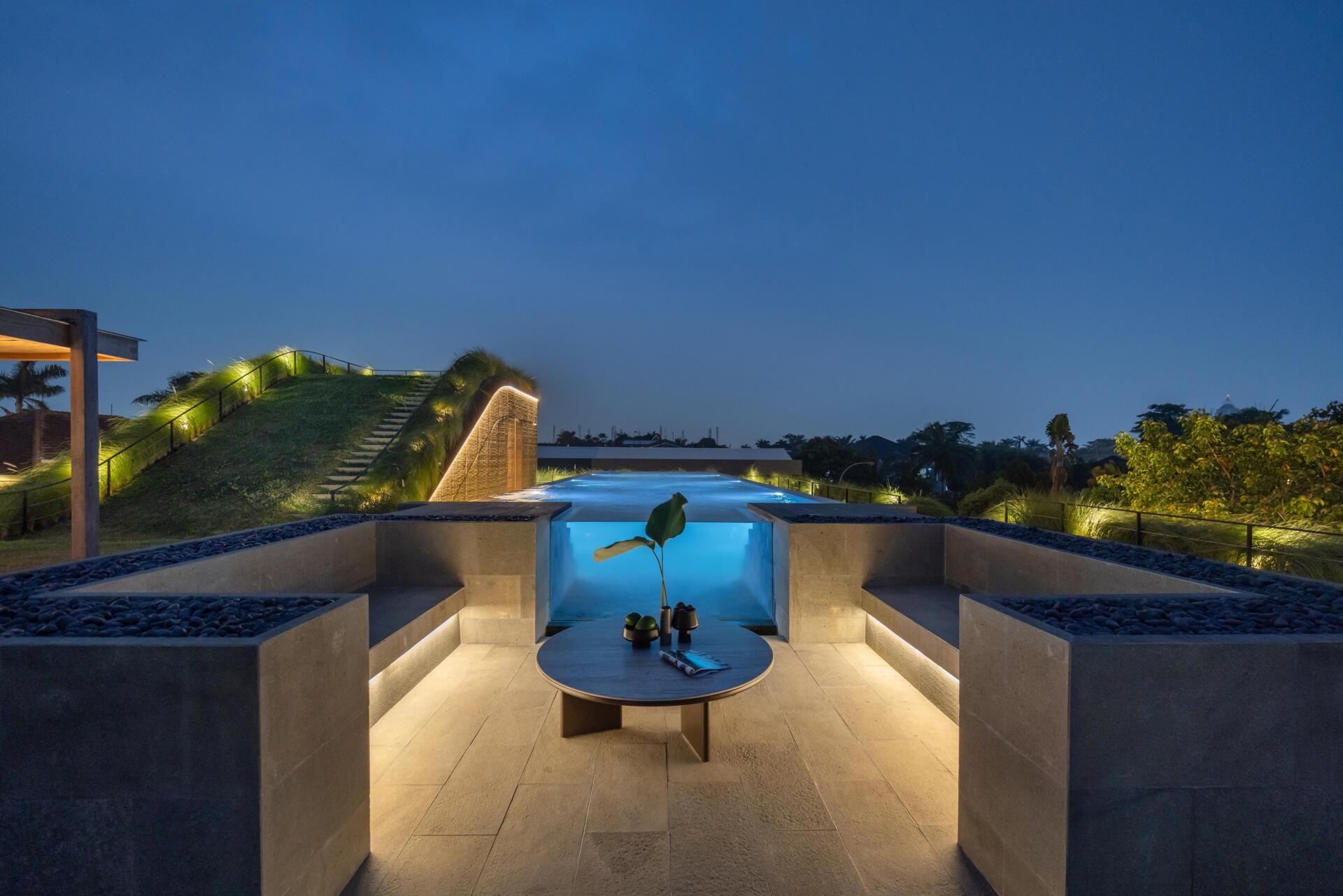 The second floor of Split Mass Residence opens toward outdoor living, with a BBQ area, sunken outdoor living room, swimming pool, gym and bathroom.