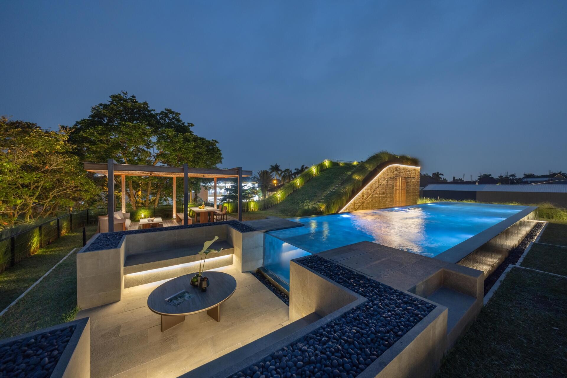 The second floor of Split Mass Residence opens toward outdoor living, with a BBQ area, sunken outdoor living room, swimming pool, gym and bathroom.