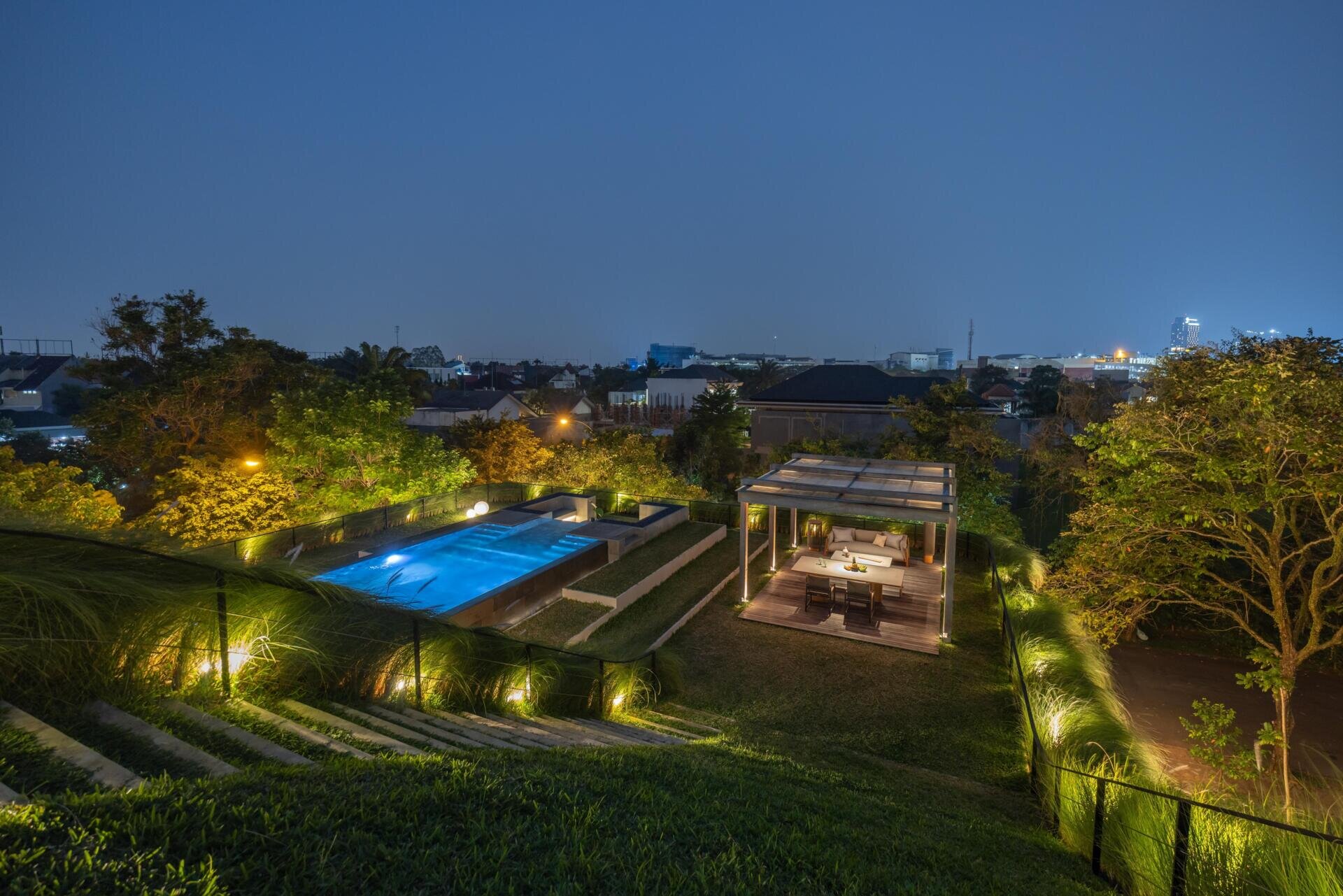 The second floor of Split Mass Residence opens toward outdoor living, with a BBQ area, sunken outdoor living room, swimming pool, gym and bathroom.