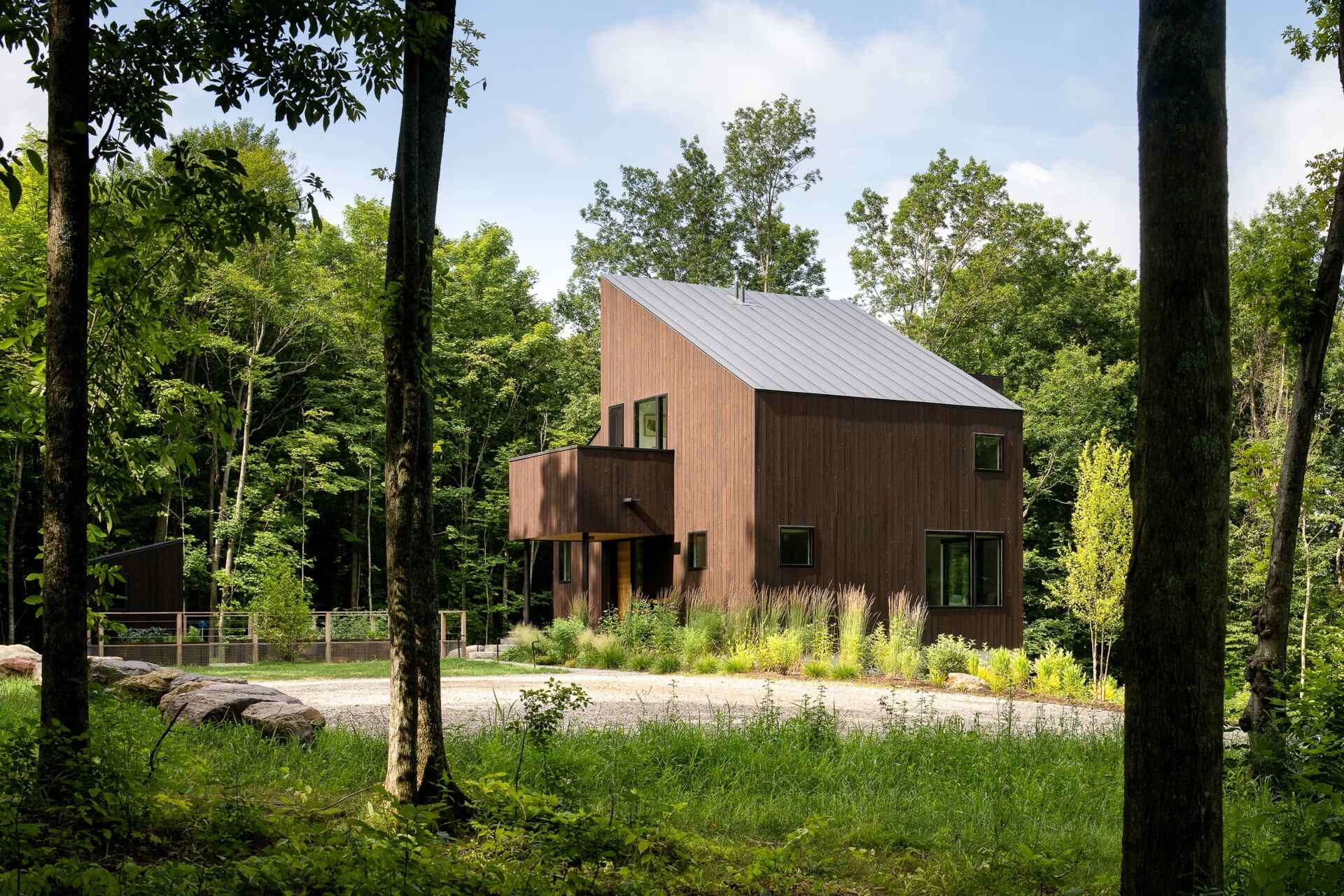 Discover the Milo House in Cornwall, Vermont, where irregular architectural volumes and dark Gendai® yakisugi siding give this hillside home a bark-like appearance among the trees.