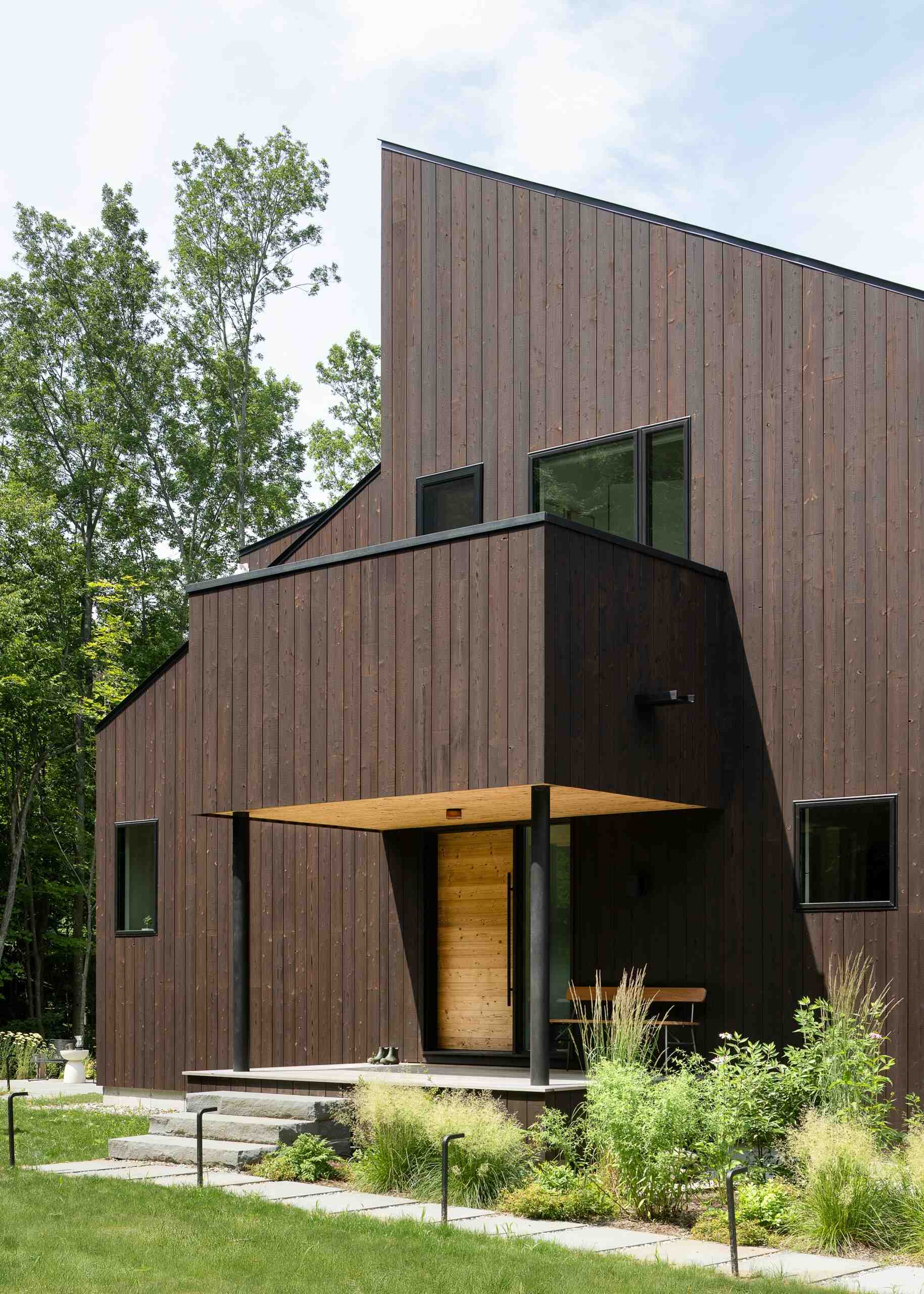 Discover the Milo House in Cornwall, Vermont, where irregular architectural volumes and dark Gendai® yakisugi siding give this hillside home a bark-like appearance among the trees.