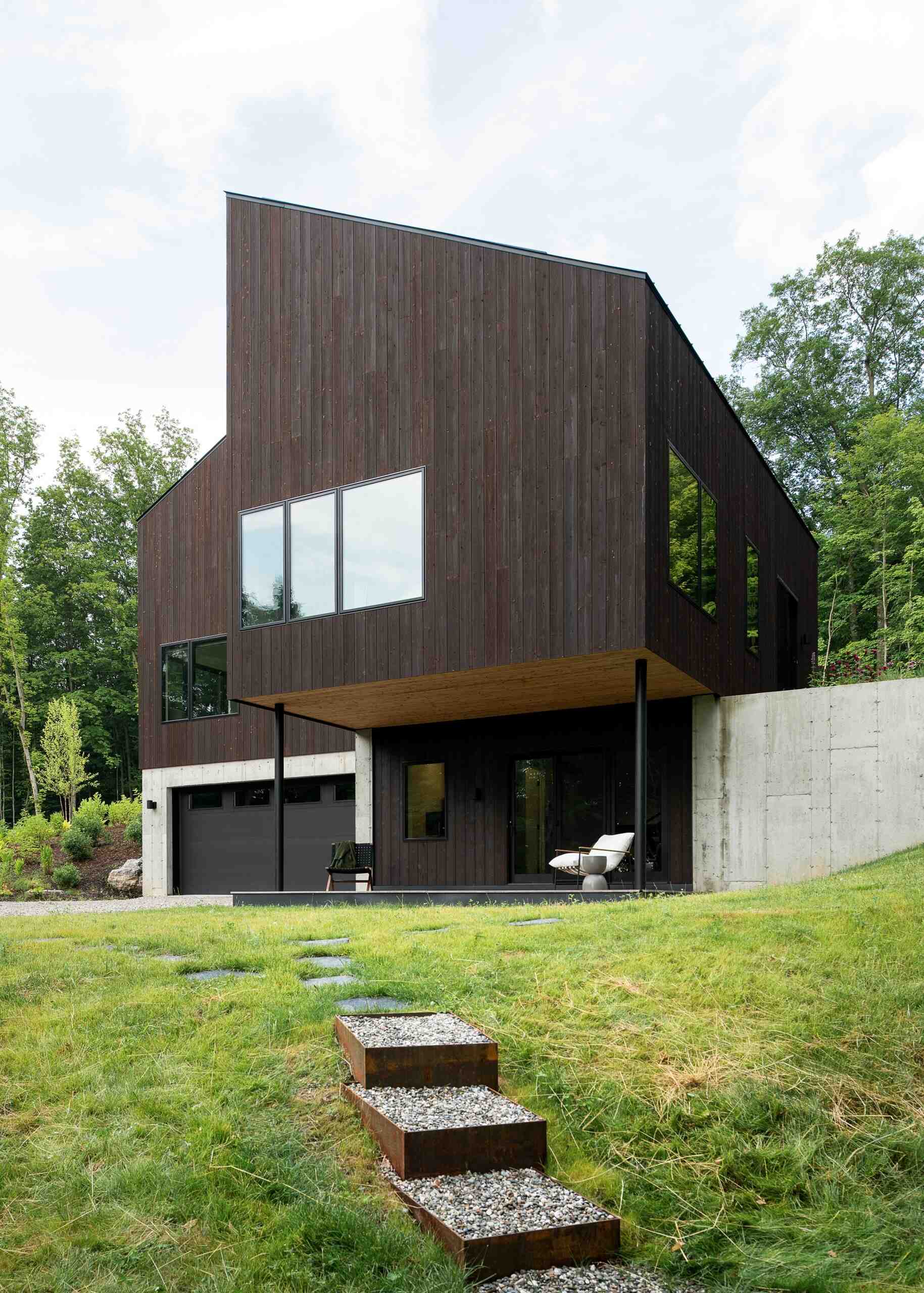 Discover the Milo House in Cornwall, Vermont, where irregular architectural volumes and dark Gendai® yakisugi siding give this hillside home a bark-like appearance among the trees.