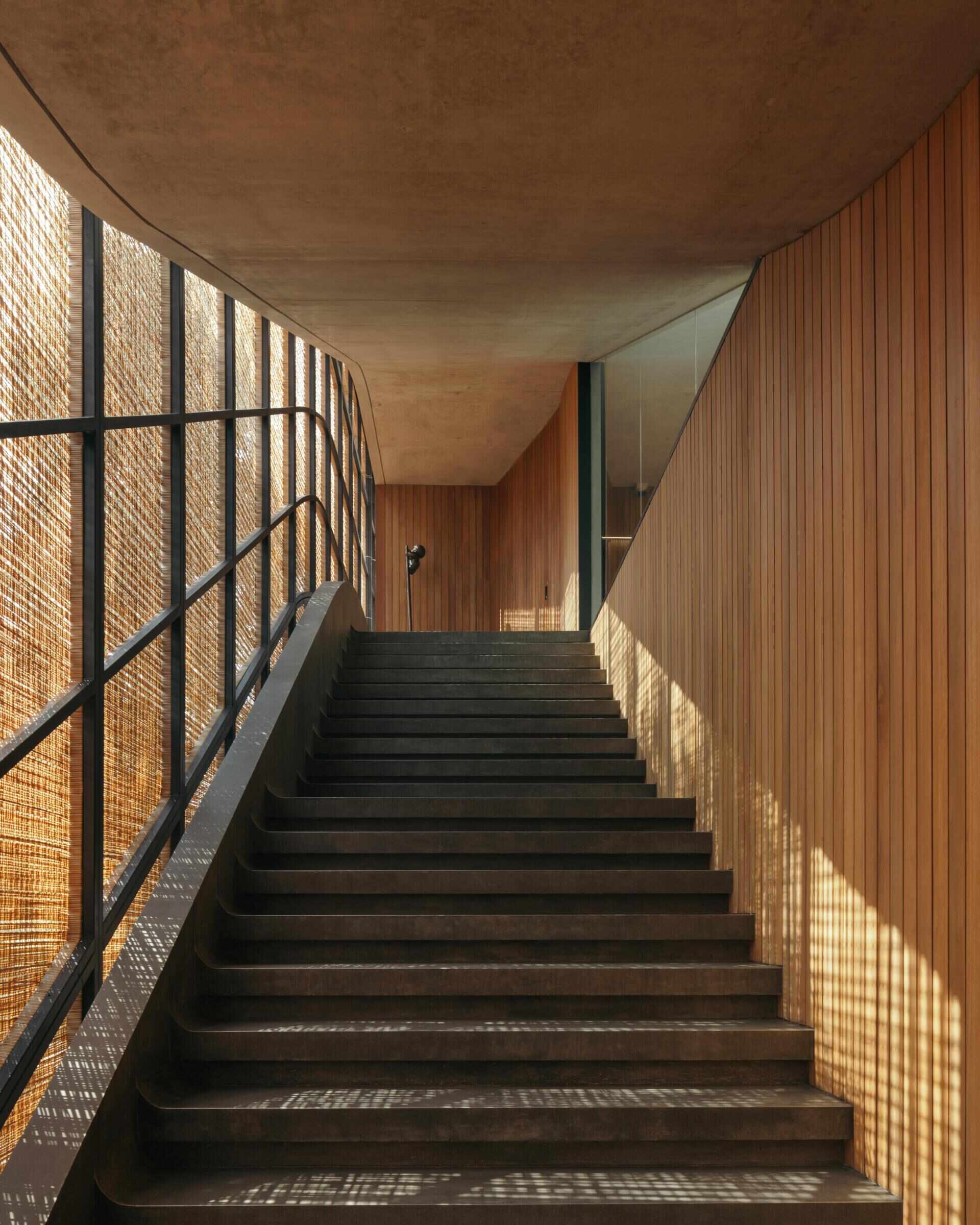 A modern house with stairs that run alongside woven screens.