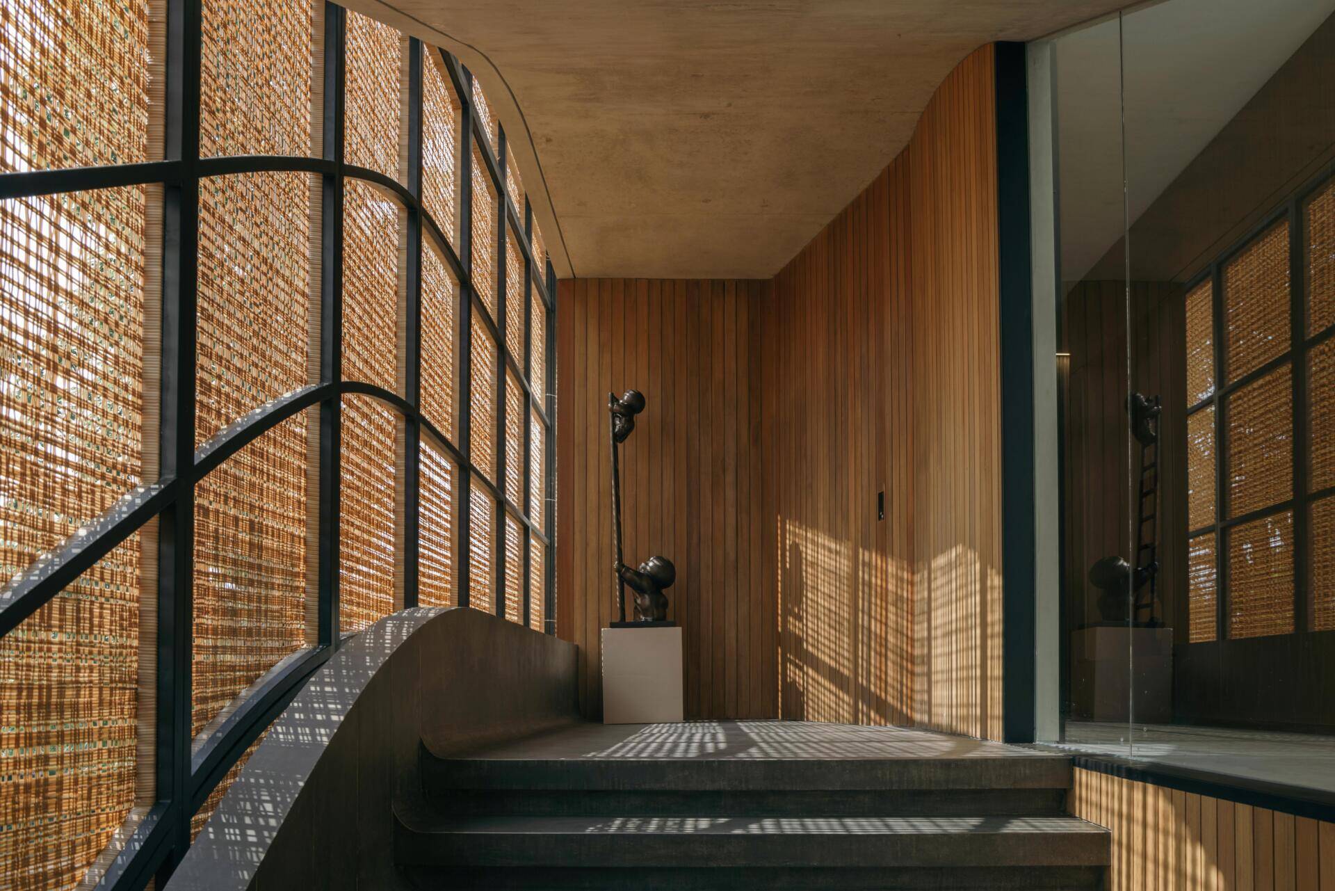 A modern house with stairs that run alongside woven screens.
