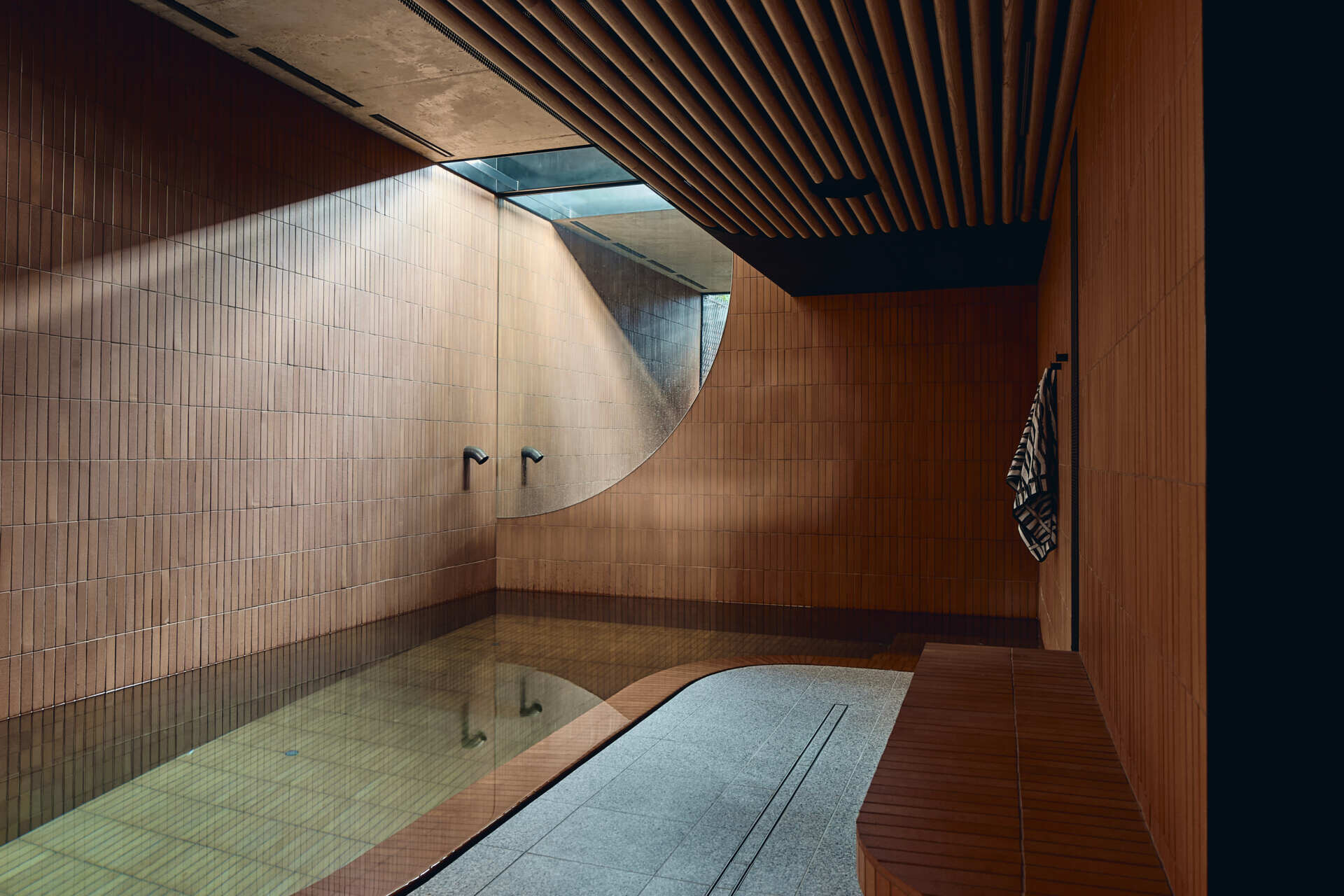An indoor pool lined with warm terracotta tiles forms part of Babylonia's underground wellness wing, alongside an infrared sauna, gym and ice bath.