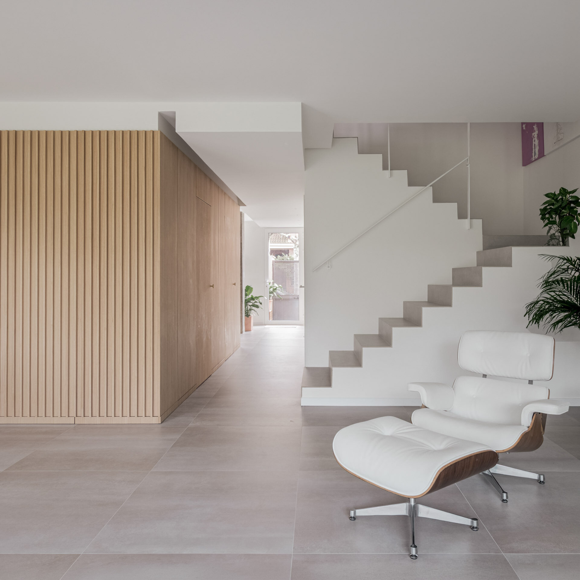 The original staircase remains in D + A House as a solid light-grey volume, joined by an exposed concrete column that preserves part of the home's original structure.