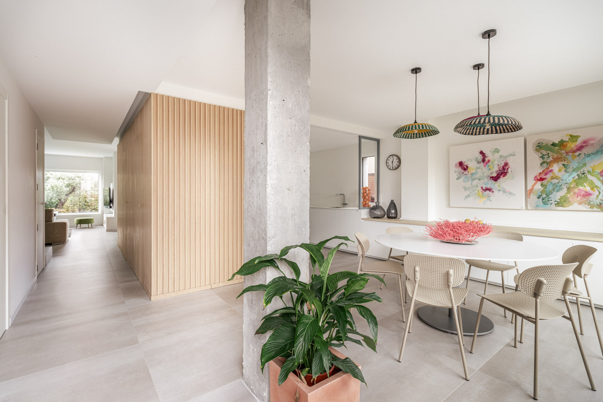 A round white dining table, perforated chairs and natural-fibre pendant lights create an informal dining area near the entrance of this Madrid home.