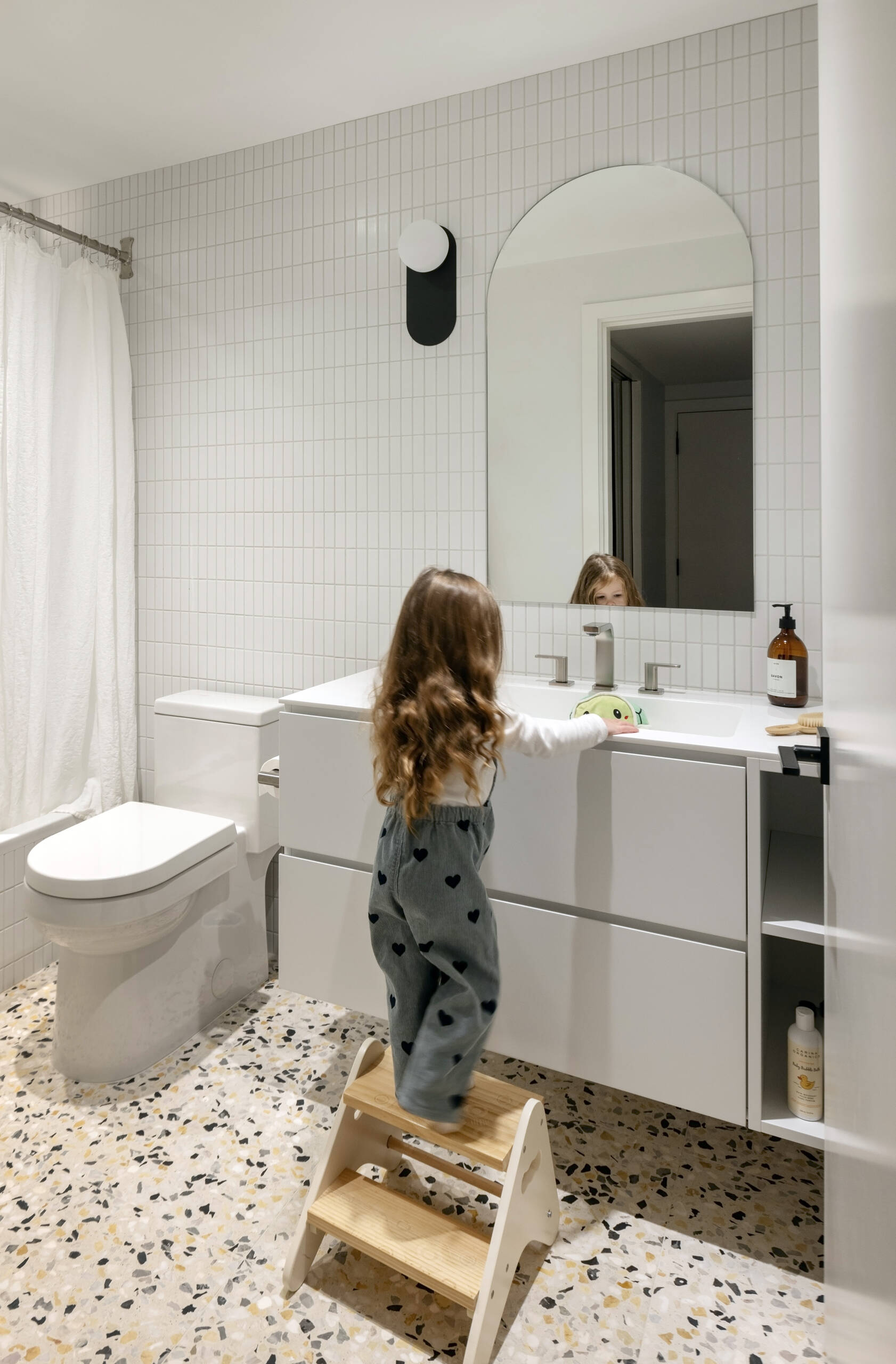 A charming children's bedroom and playful terrazzo bathroom feature in the lower level of this renovated West Vancouver mid-century home, designed for a growing family.