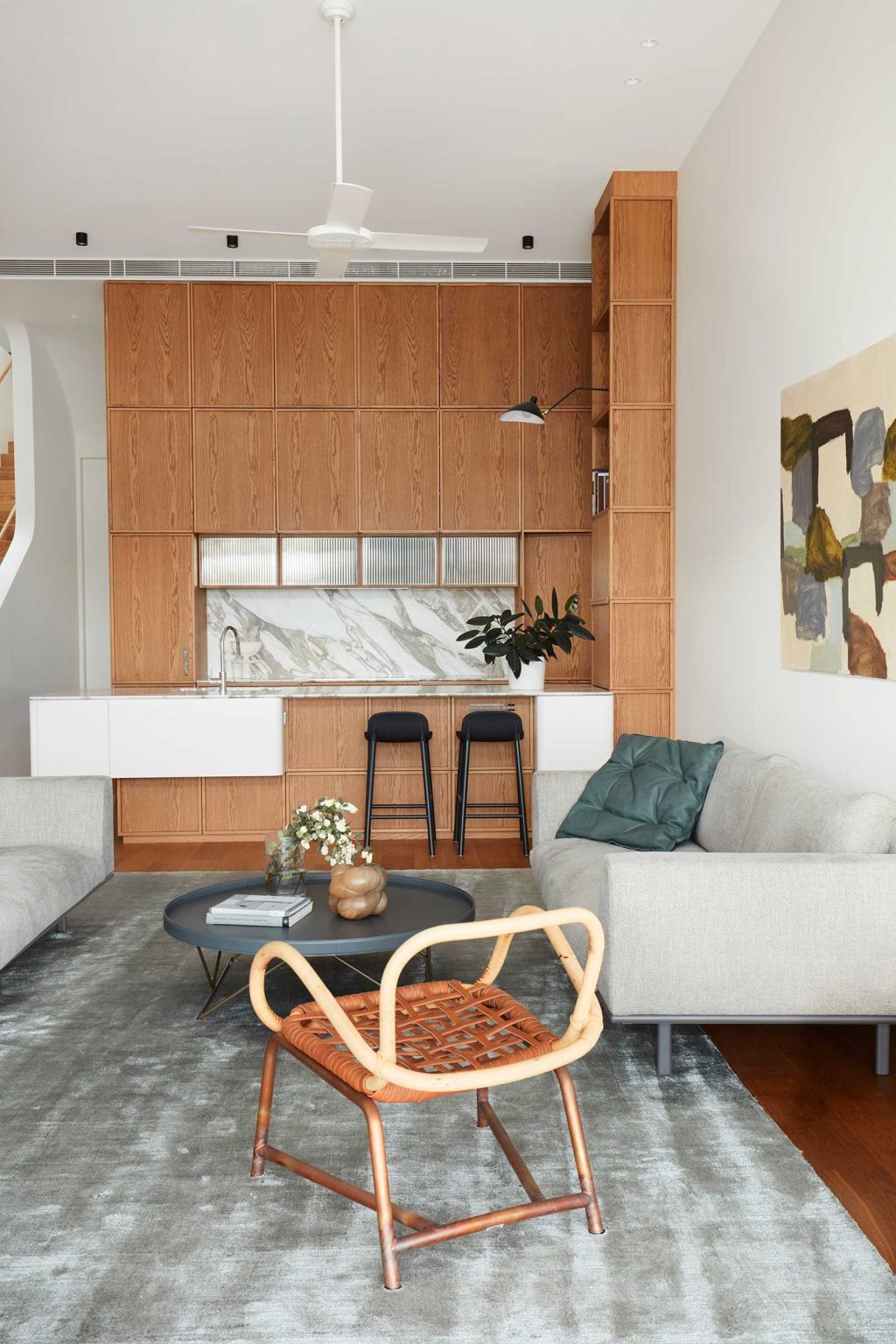 Tall wood cabinets, a seating peninsula and a vertical window shape the kitchen inside Earth-Ship, the Sydney home renovated by Luigi Rosselli Architects.