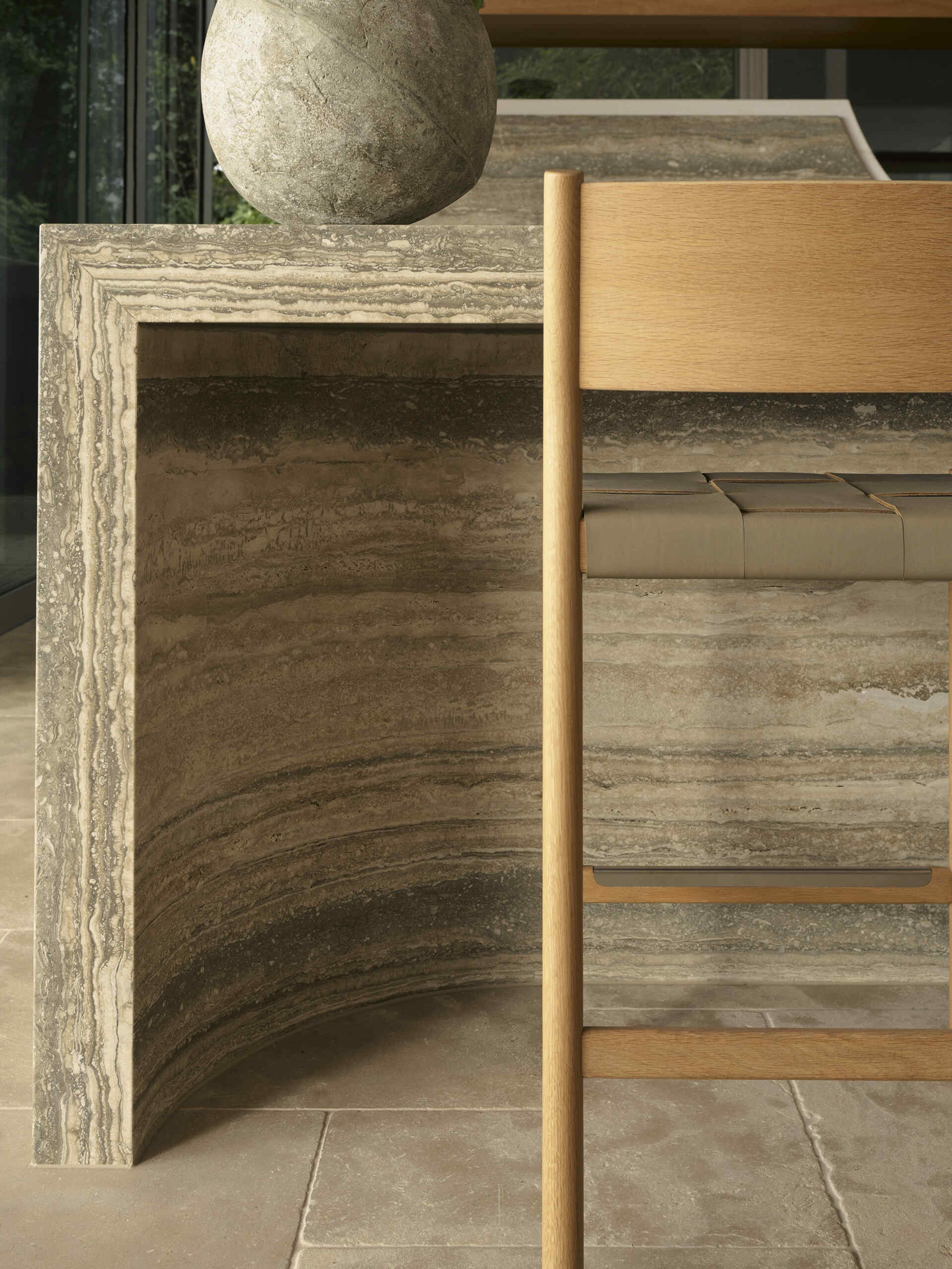 Step inside this Byron Bay kitchen featuring ocean-blue travertine, curved details, spliced stone and textured porcelain, paired with warm timber and expansive views across Wategos Beach.