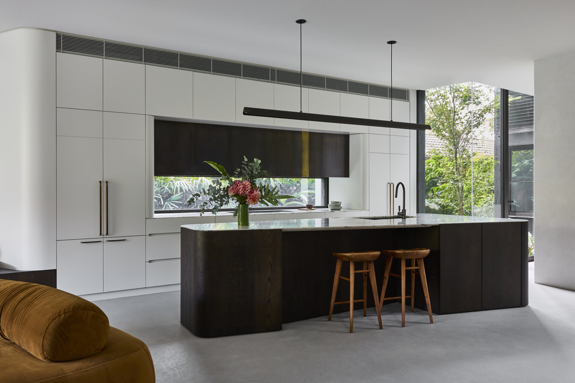 Tour the contemporary kitchen at Sasso Nero, where dark oak, pale stone and crisp white cabinetry create a refined contrast. Garden views, bronze-toned details and a slim linear pendant complete the space.