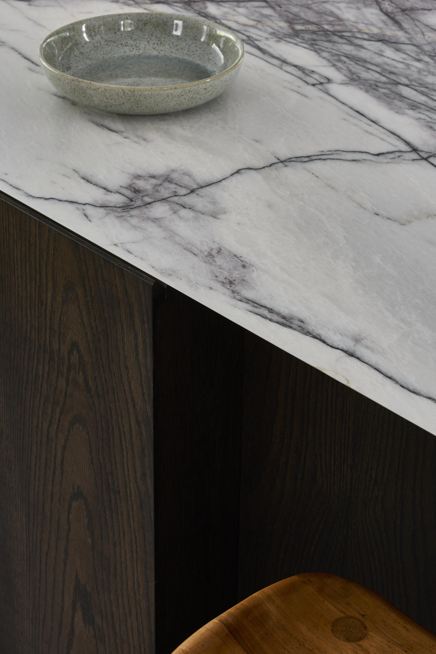 Tour the contemporary kitchen at Sasso Nero, where dark oak, pale stone and crisp white cabinetry create a refined contrast. Garden views, bronze-toned details and a slim linear pendant complete the space.