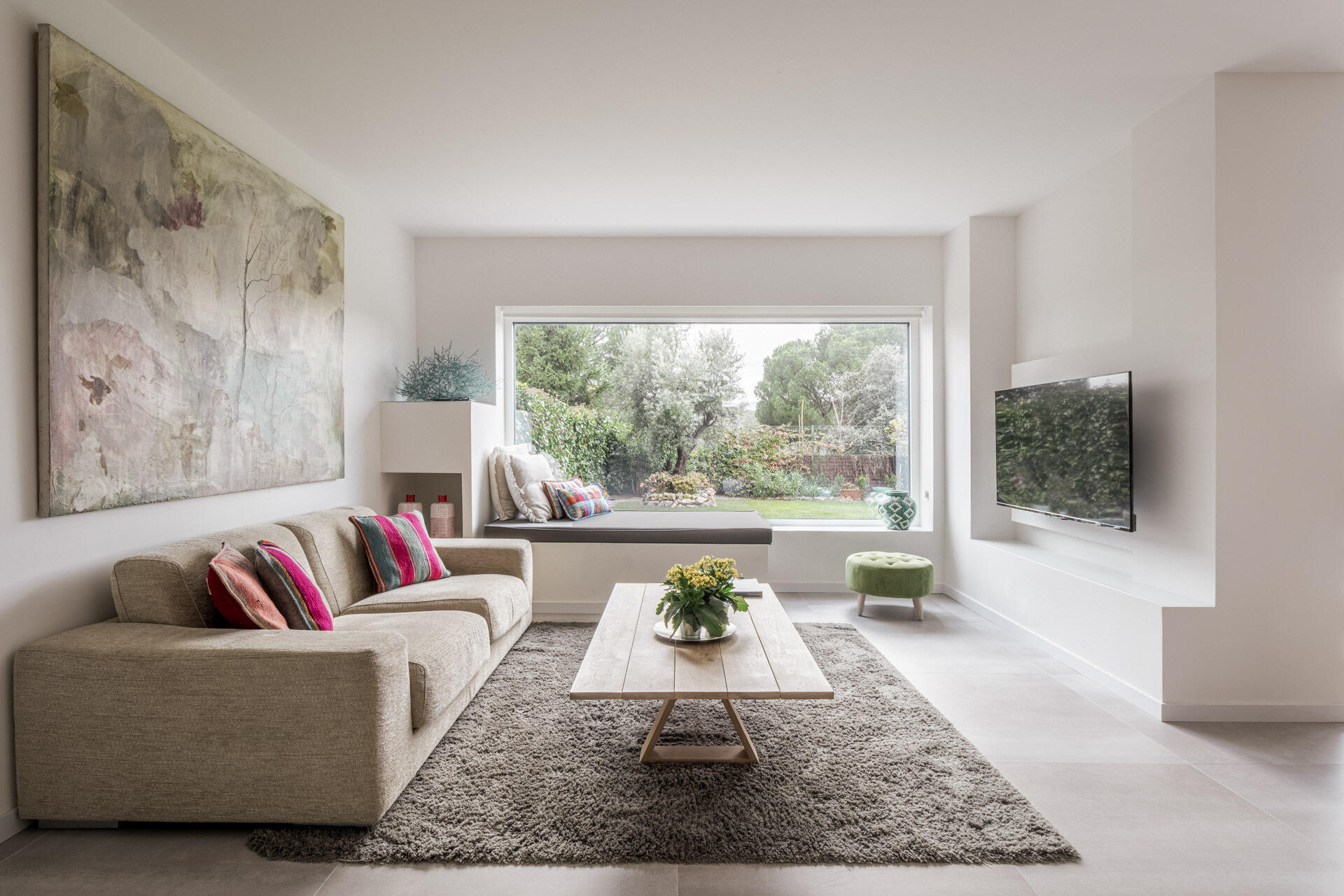 The living room shares the garden-facing side of D + A House, with white finishes, light flooring and concealed sliding glass doors helping maintain an open plan.