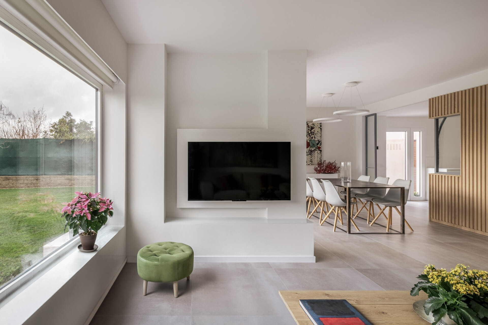 The living room shares the garden-facing side of D + A House, with white finishes, light flooring and concealed sliding glass doors helping maintain an open plan.