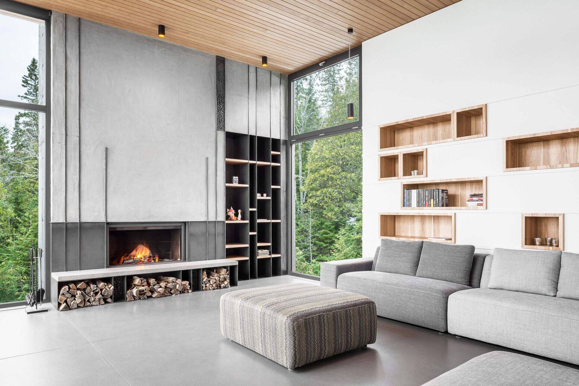 Explore the living room of Long Horizontals, where wood-lined shelving, a concrete fireplace and an open floor plan create a warm contemporary interior.