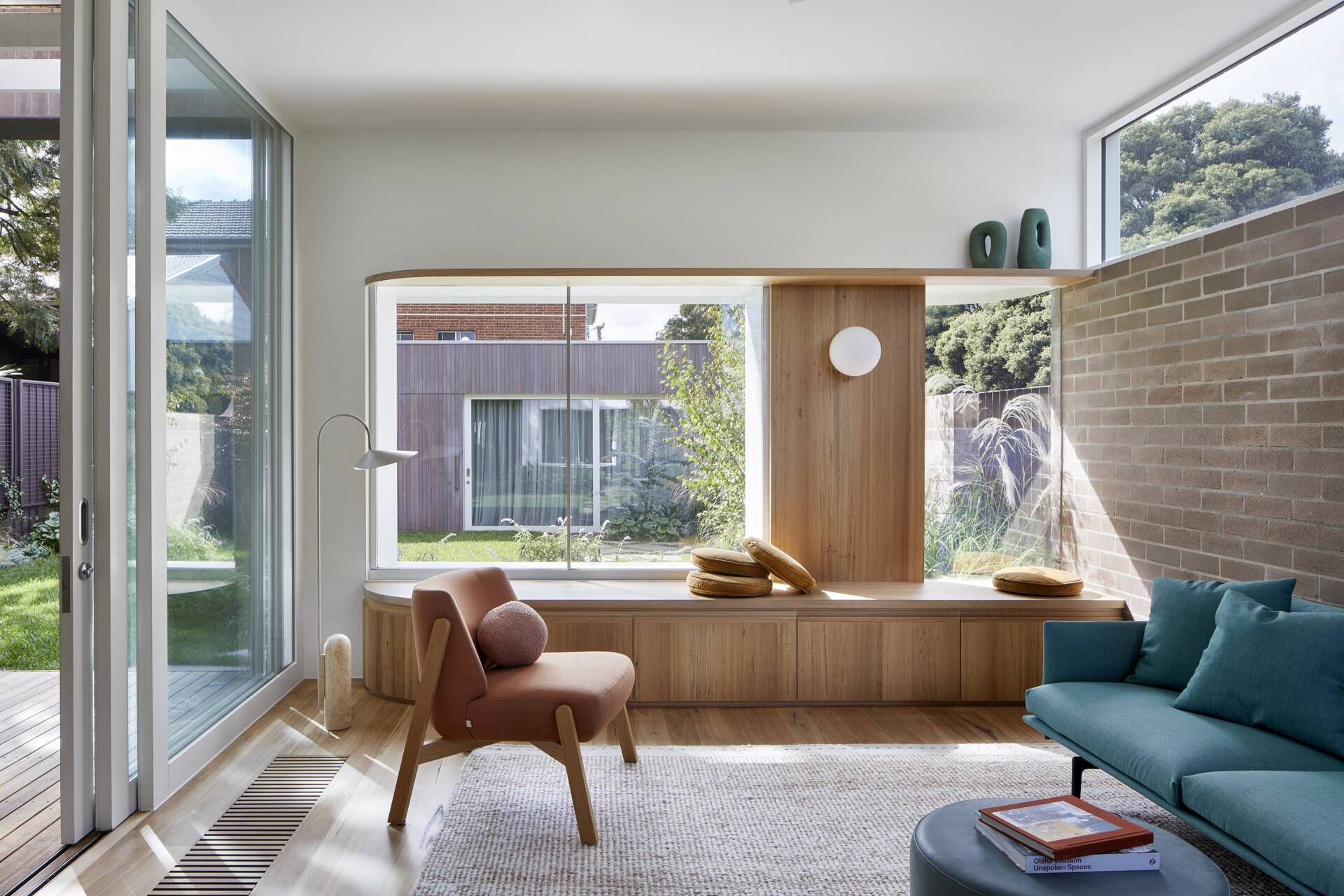 A screenless Melbourne lounge features a comfortable window seat, generous views and a curved staircase that passes between the living and dining spaces.