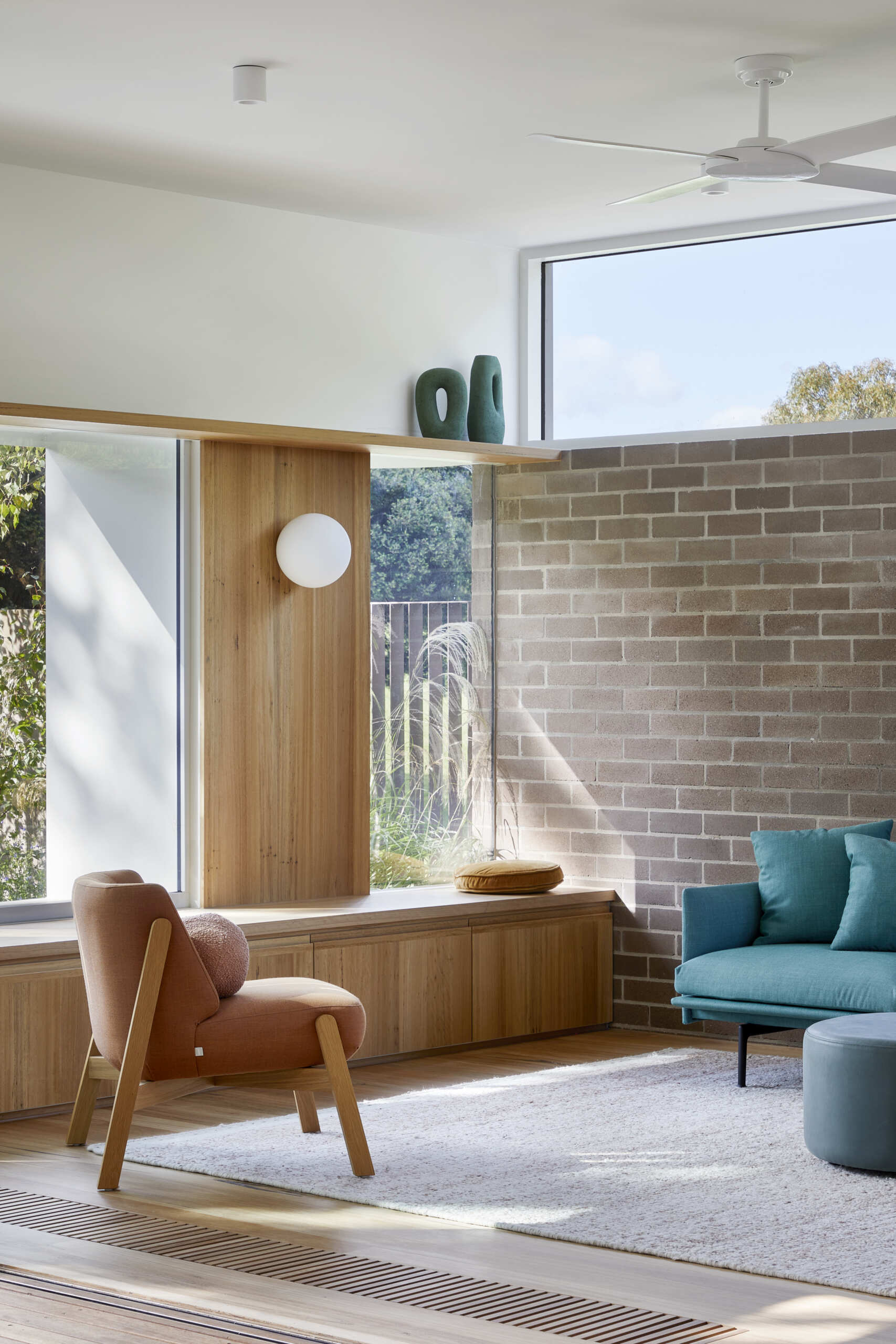 A screenless Melbourne lounge features a comfortable window seat, generous views and a curved staircase that passes between the living and dining spaces.