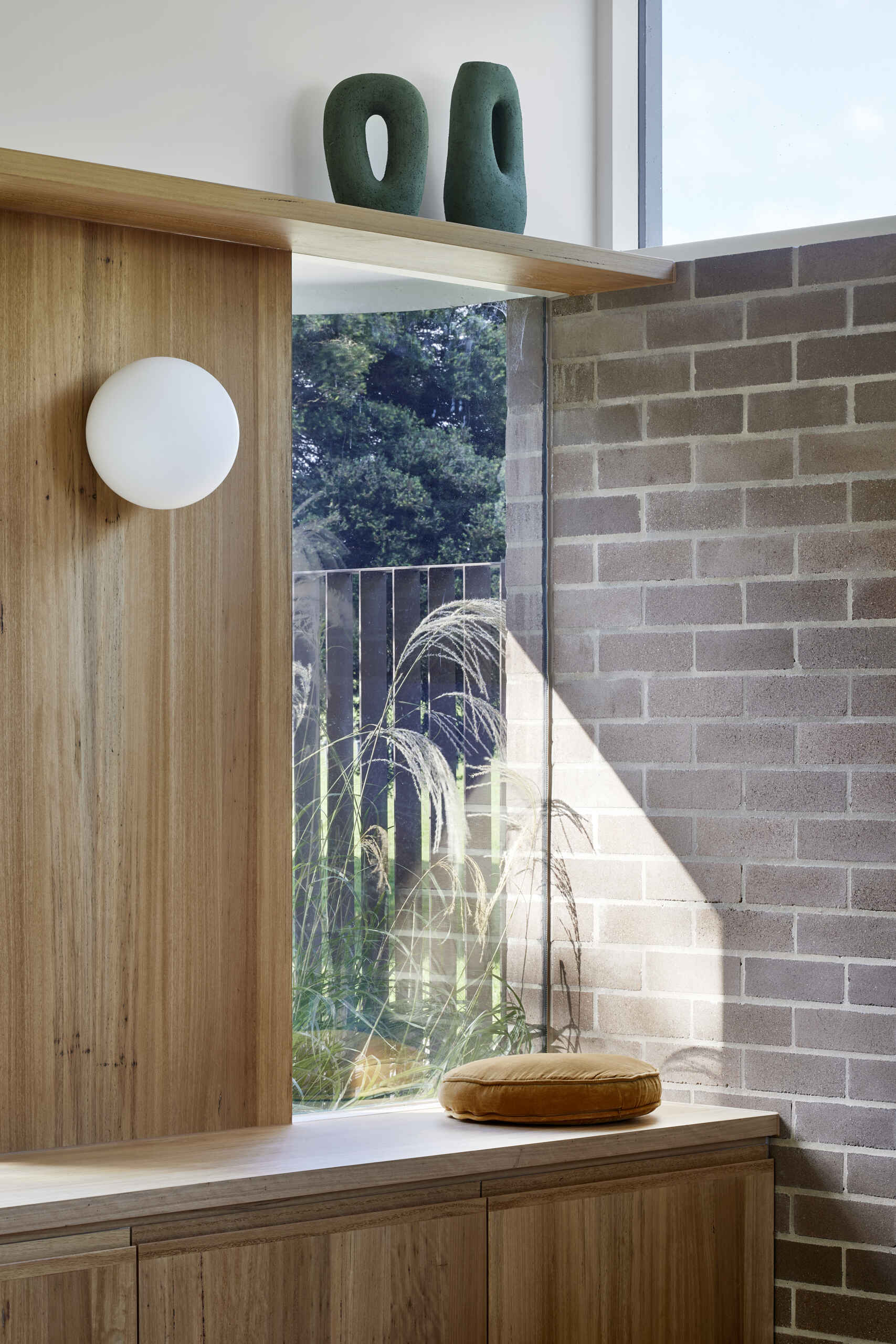 A screenless Melbourne lounge features a comfortable window seat, generous views and a curved staircase that passes between the living and dining spaces.