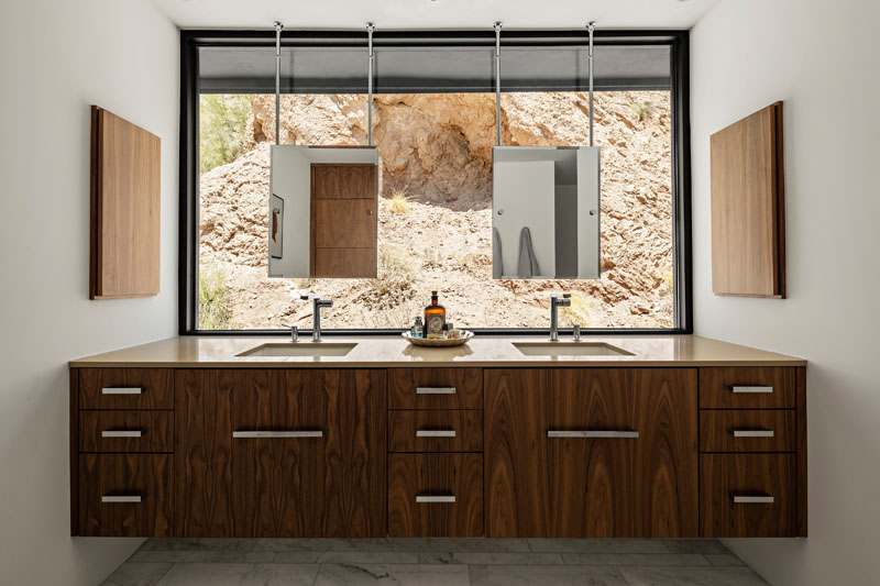A large window in the master bathroom turns Camelback Mountain into the backdrop for the mirrors, bringing the red rock landscape directly into the interior of this Phoenix home.