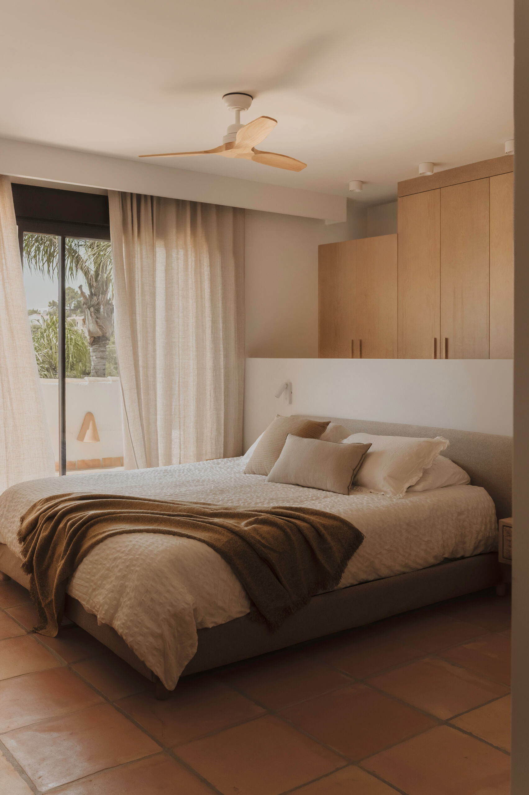 Warm oak joinery, terracotta floors and soft linen fabrics come together in a main bedroom that feels bright, simple and inviting.