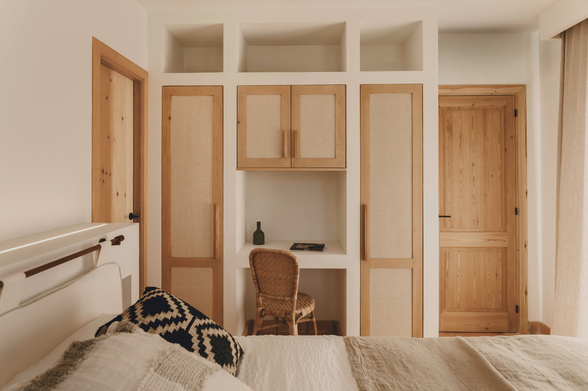 Oak wardrobes with woven natural-fibre fronts and a built-in desk give this Mediterranean bedroom texture and timeless appeal.