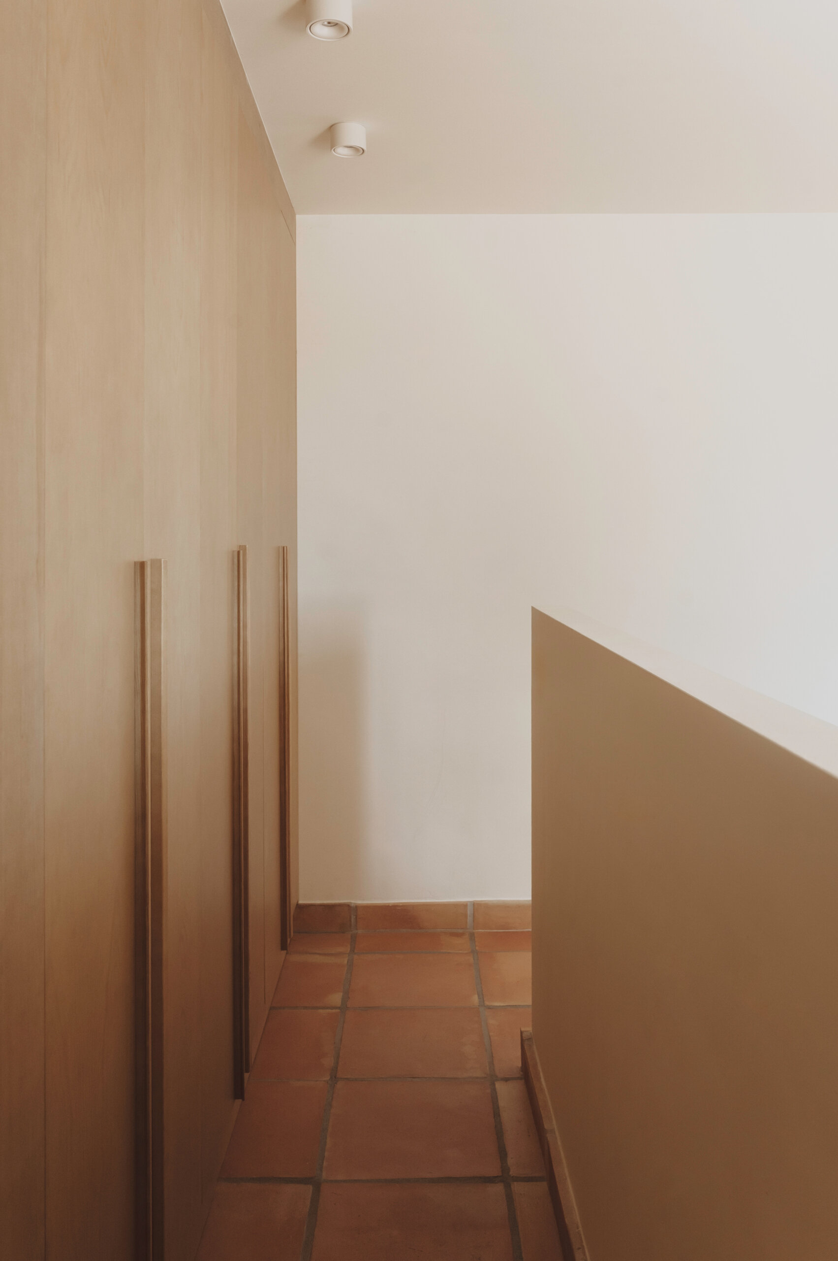 Warm oak joinery, terracotta floors and soft linen fabrics come together in a main bedroom that feels bright, simple and inviting.