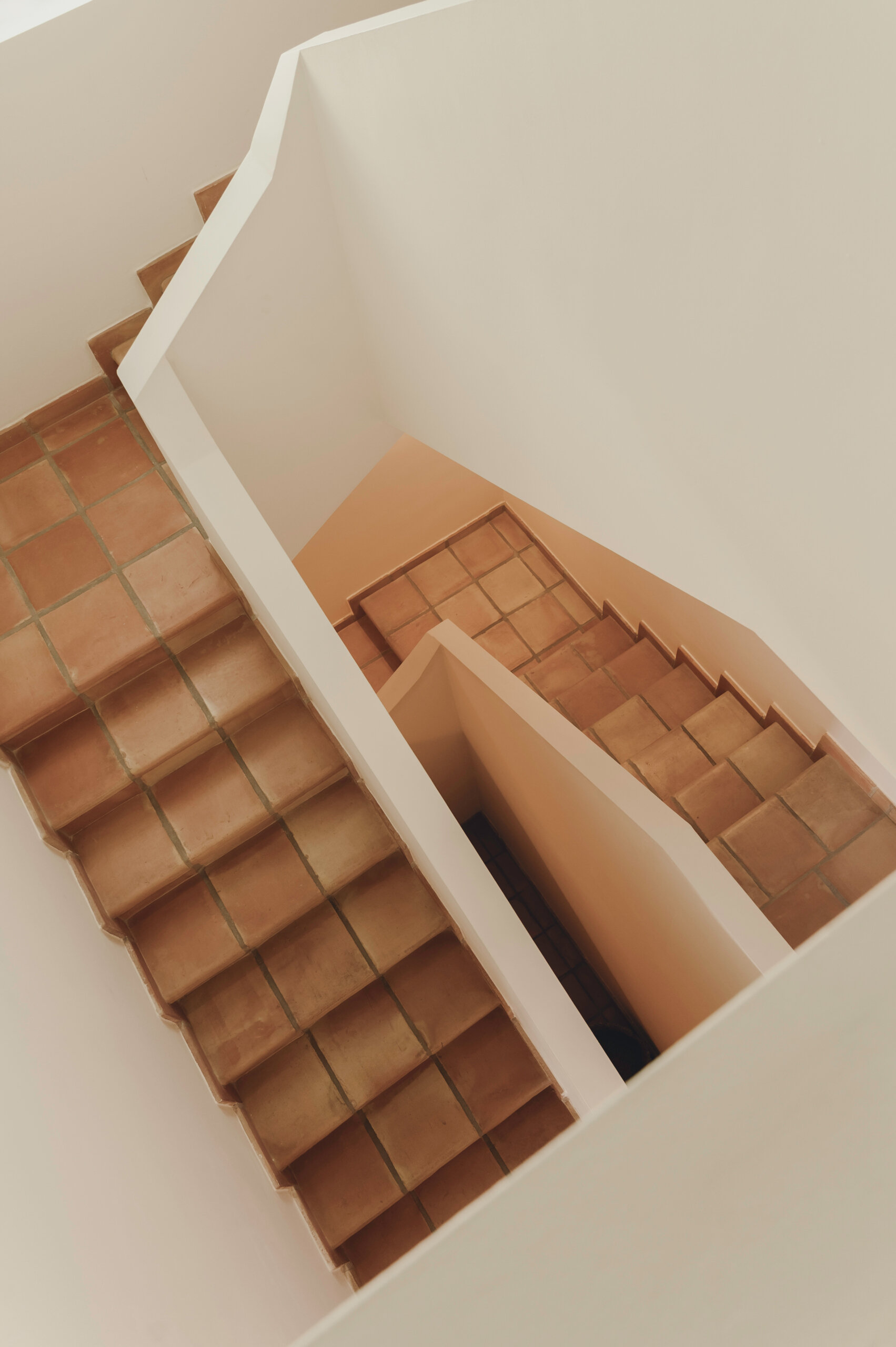 The staircase continues the home's terracotta palette, creating a seamless connection between every level.