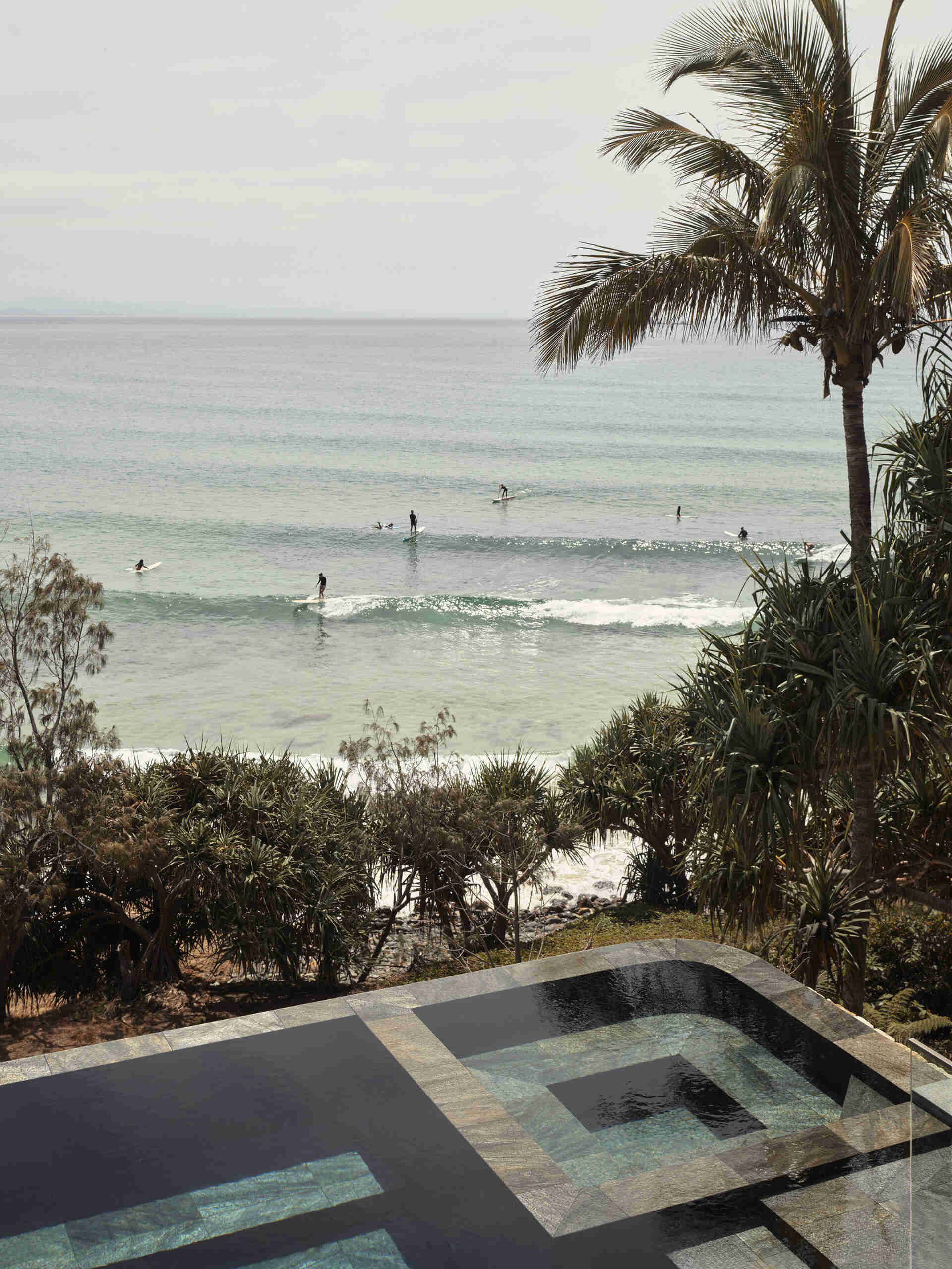 A 20-metre infinity pool sits along the edge of this Byron Bay home, with a Perspex pool edge visually connecting the water to the ocean and an outdoor shower completing the coastal setting.