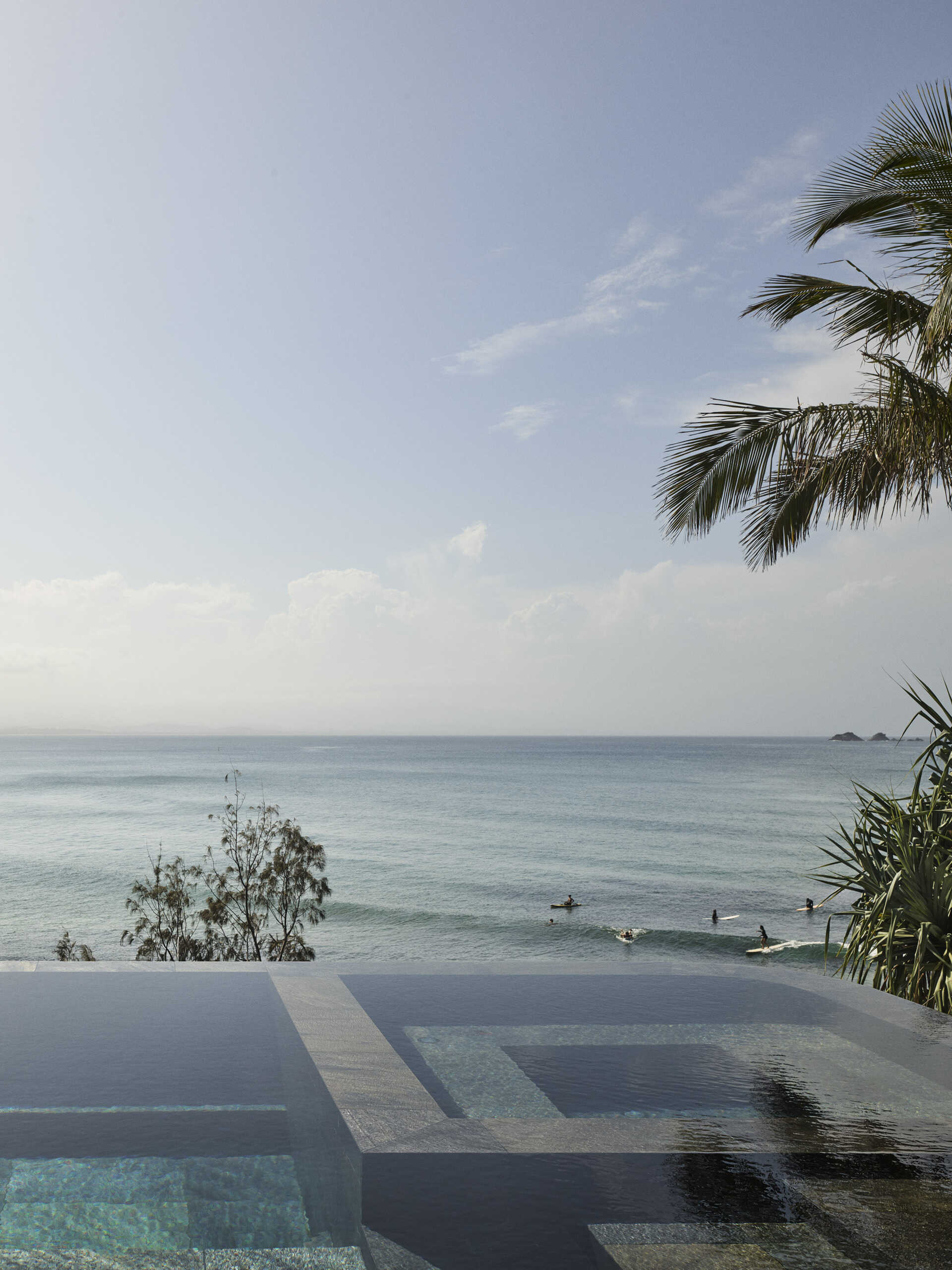 A 20-metre infinity pool sits along the edge of this Byron Bay home, with a Perspex pool edge visually connecting the water to the ocean and an outdoor shower completing the coastal setting.