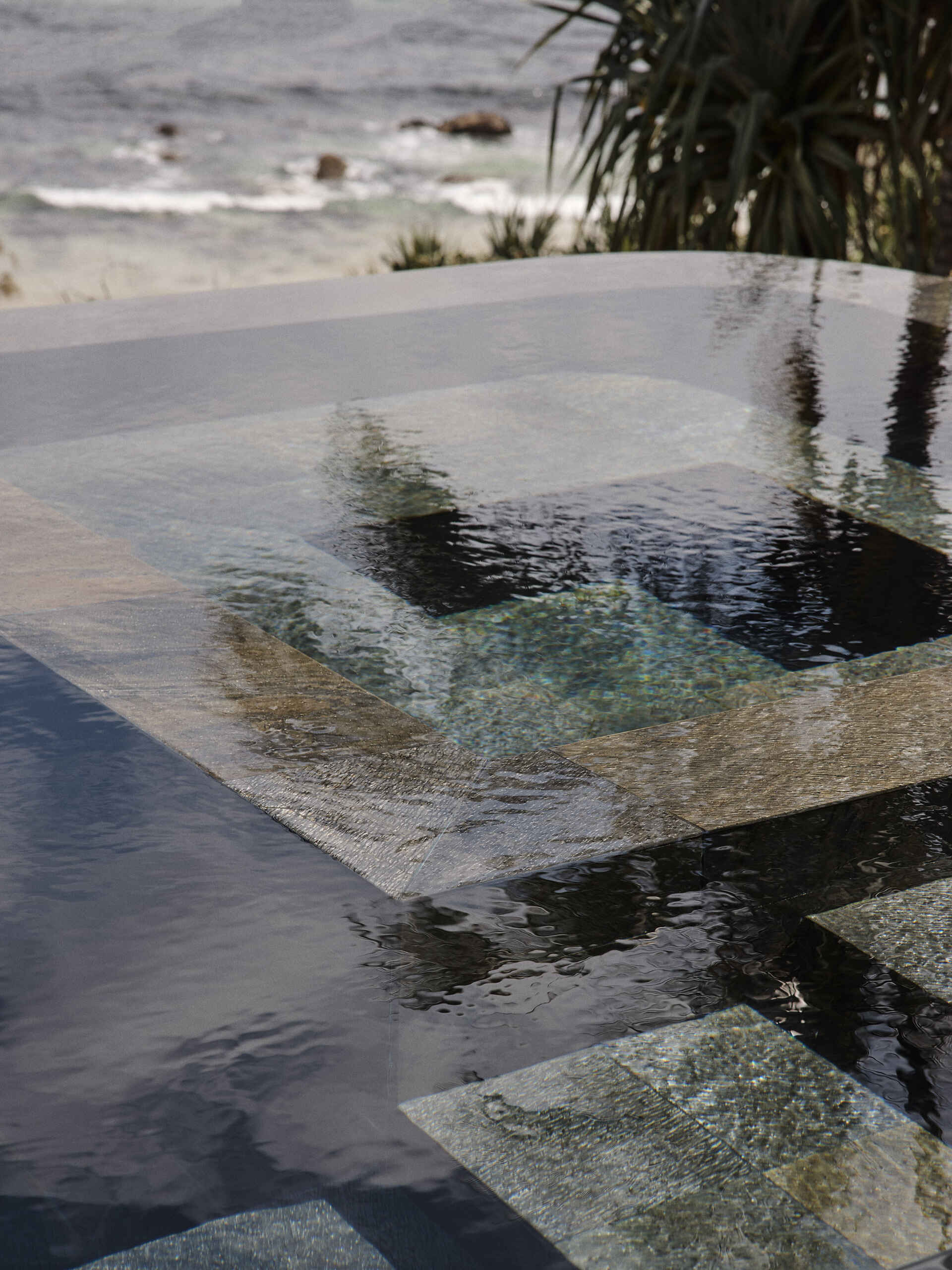 A 20-metre infinity pool sits along the edge of this Byron Bay home, with a Perspex pool edge visually connecting the water to the ocean and an outdoor shower completing the coastal setting.