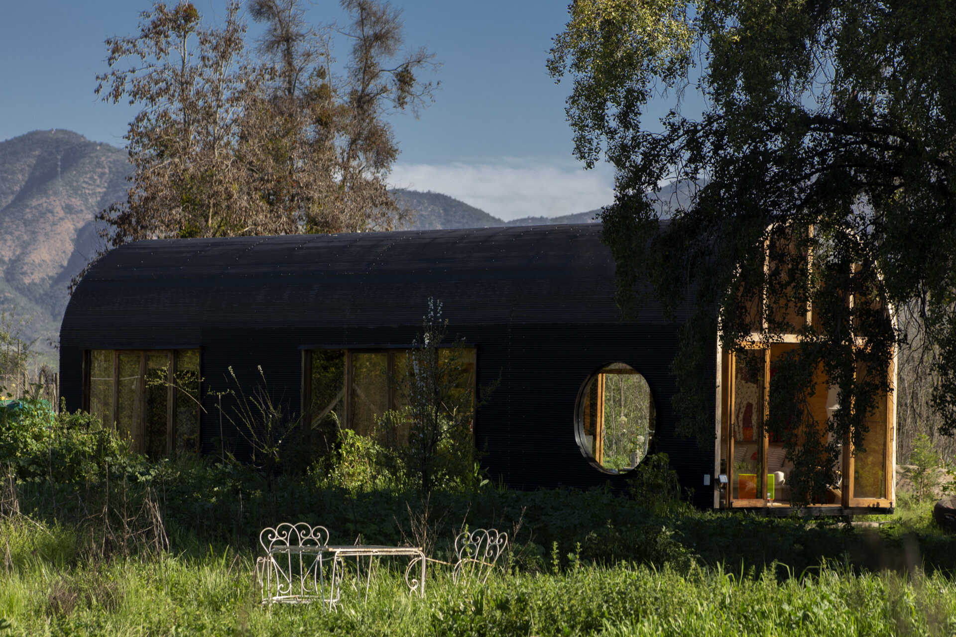 Catalejo by Tololo Ugarte is a circular tiny house elevated above the ground so seasonal grasses can grow beneath it, while its shape frames a forest of centuries-old trees.