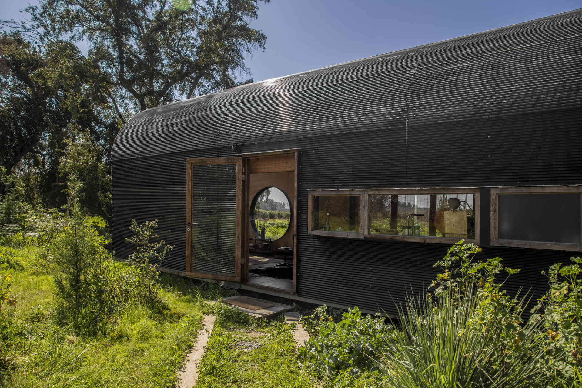 Catalejo by Tololo Ugarte is a circular tiny house elevated above the ground so seasonal grasses can grow beneath it, while its shape frames a forest of centuries-old trees.