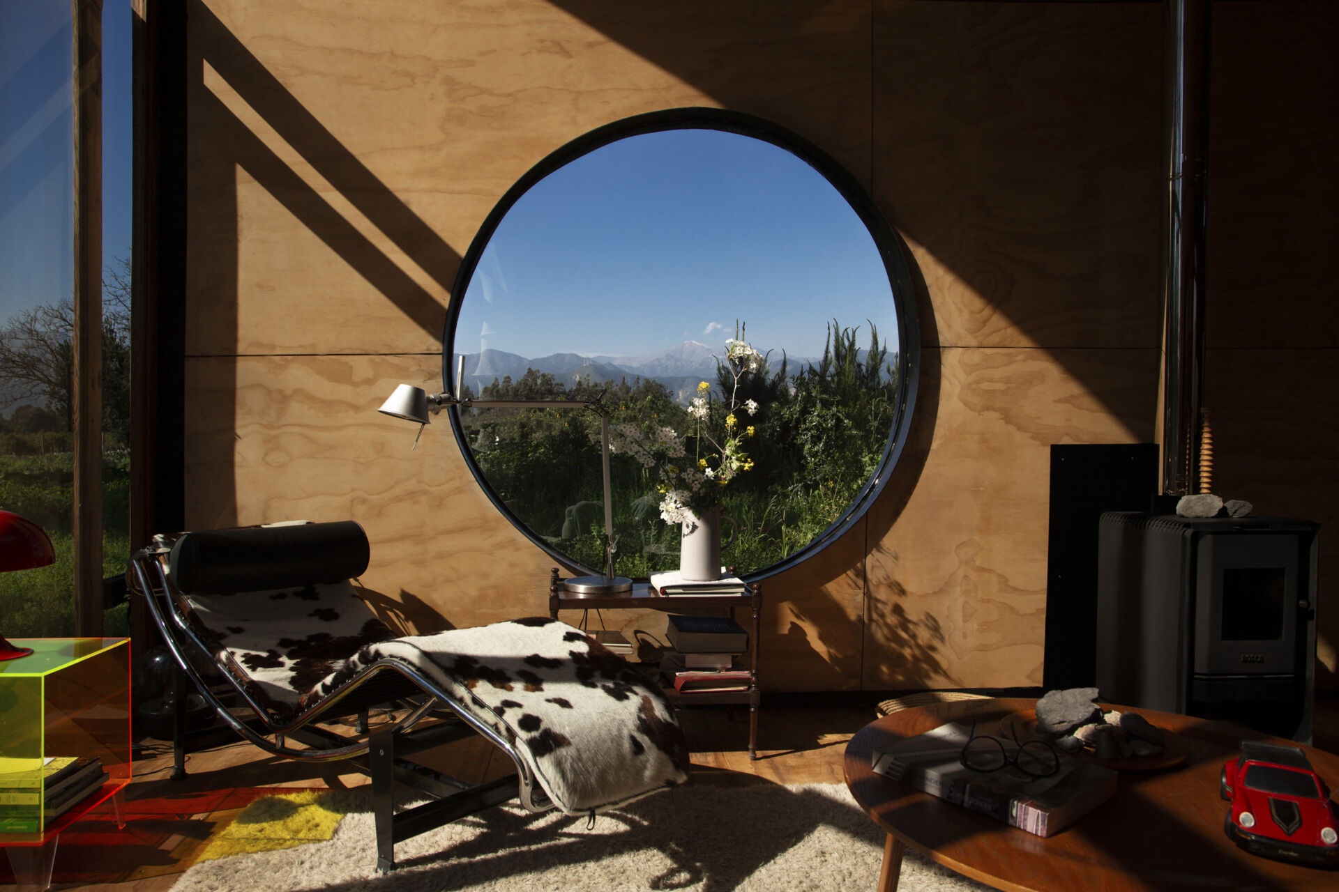 The living area in Catalejo uses double-height ceilings and expansive views to make a compact tiny house feel open and immersed in nature.