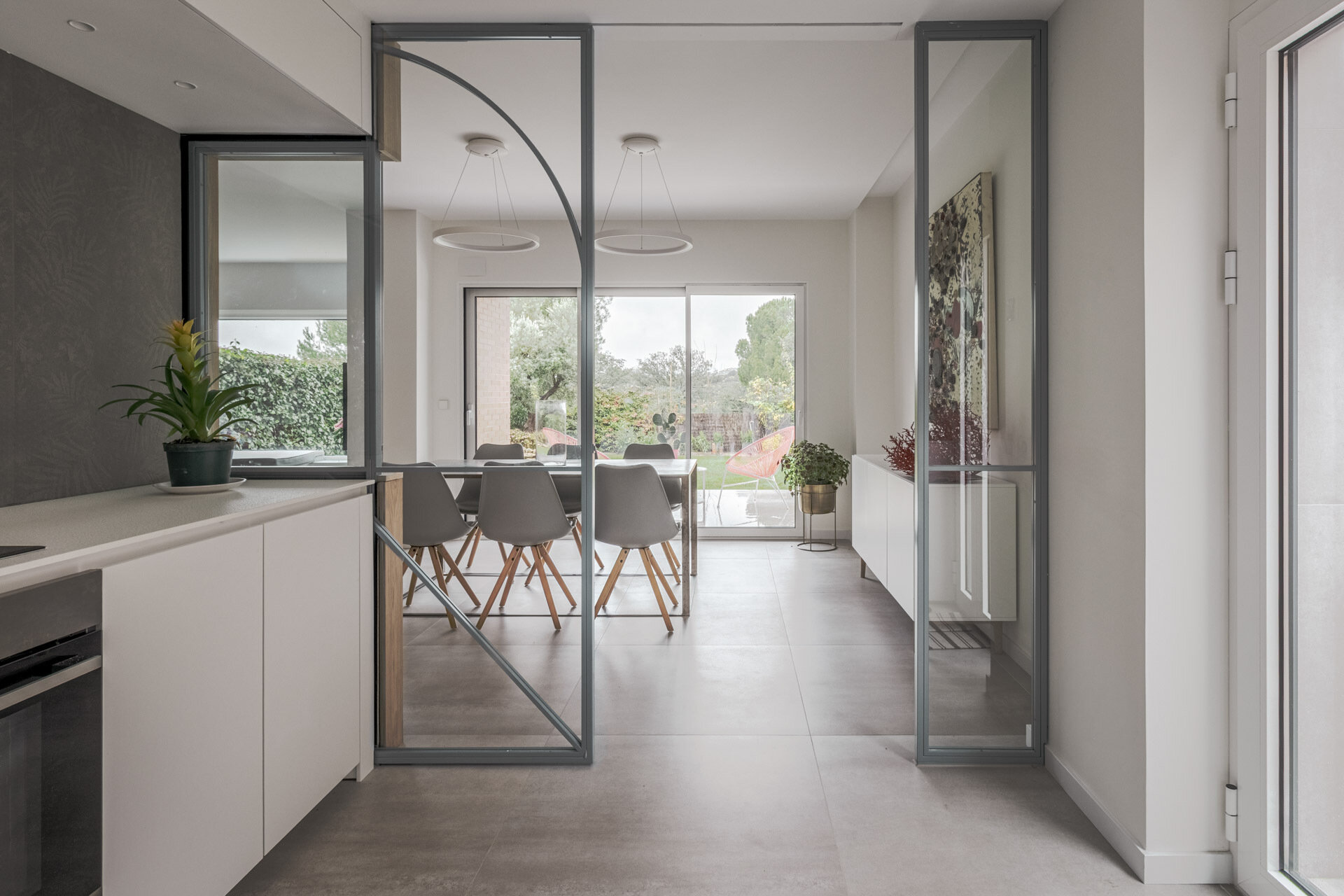 A long industrial-style dining table, Nordic chairs and garden views define the main dining area at the opposite end of this Madrid home.