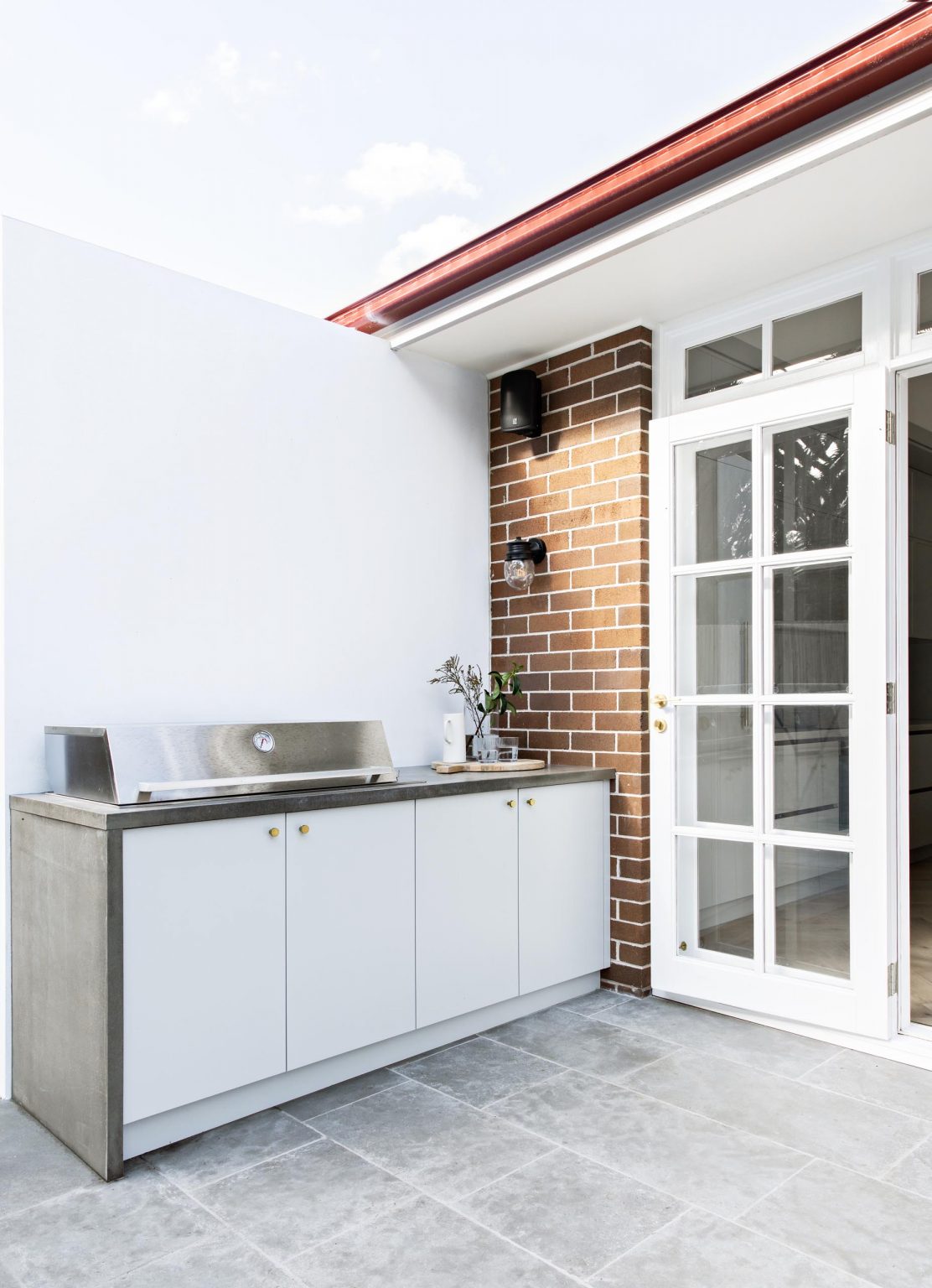 Discover the rear patio of this Concord Californian Bungalow, where two sets of French doors open from the interior onto outdoor seating and a dedicated barbecue area.