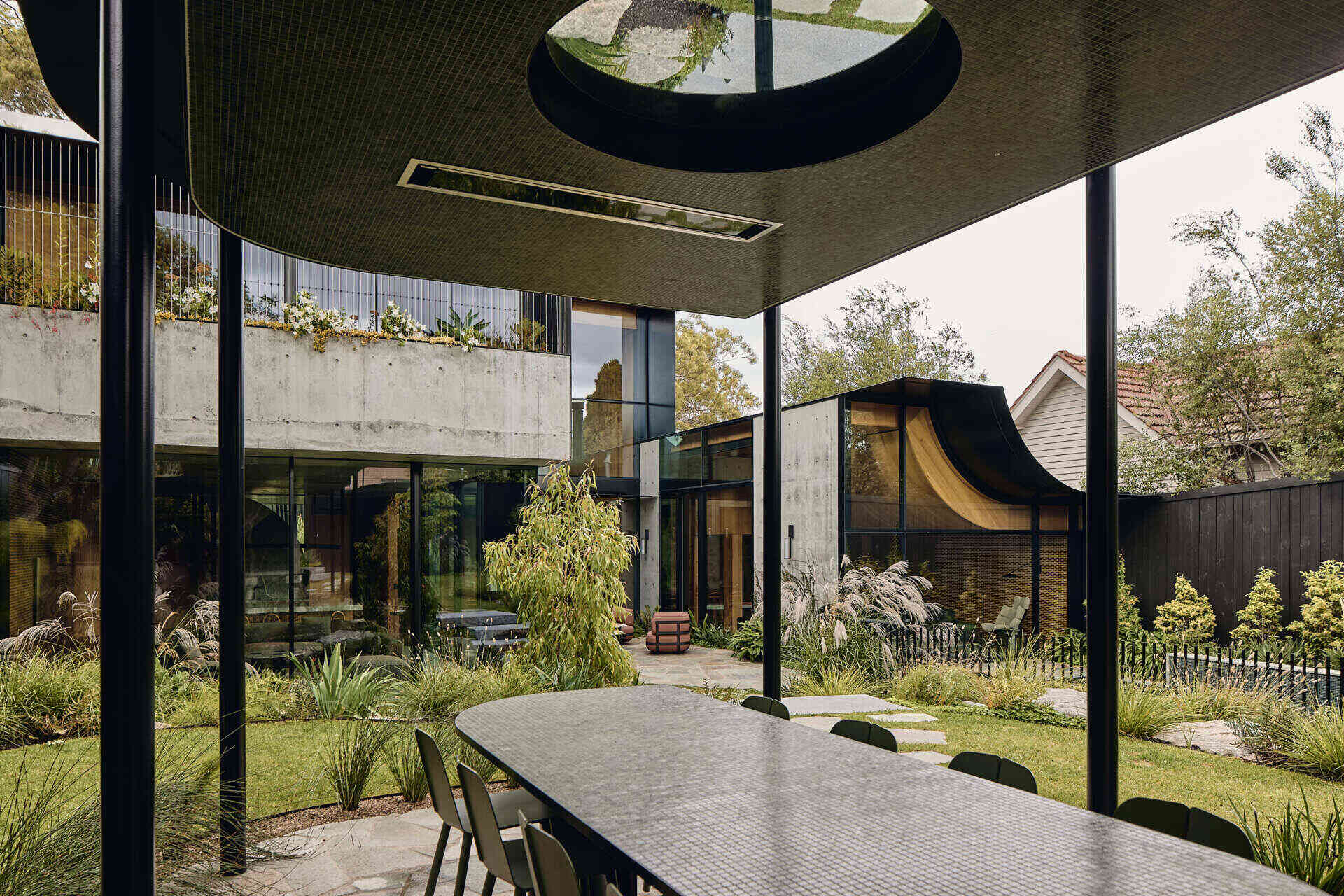 Lush terraced gardens surround the rear of Babylonia in Melbourne, where a blackened steel outdoor dining pavilion sits among the planting beside the pool.