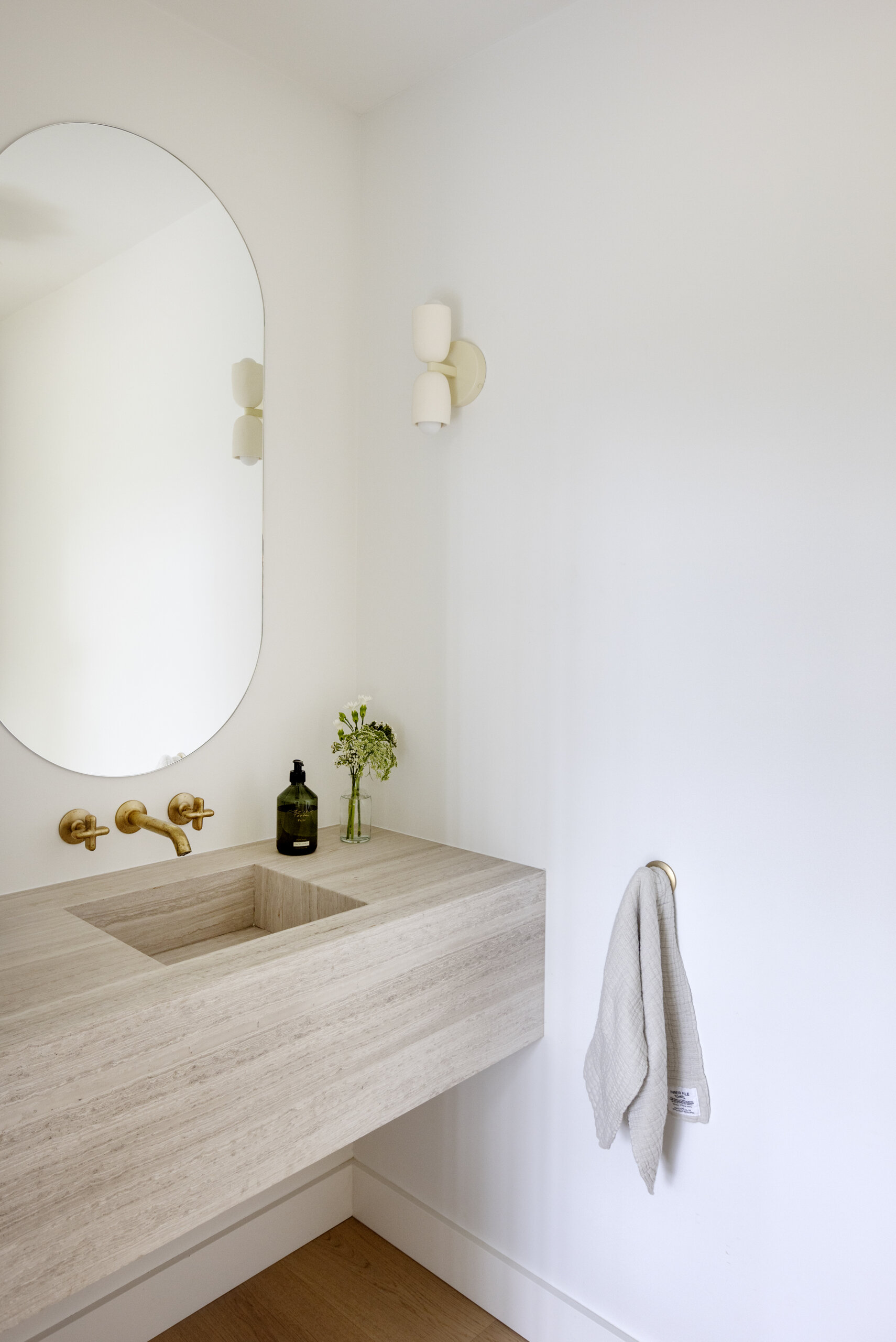 Take a look inside the streamlined powder room at Westport Place House, featuring a wall-mounted limestone counter and integrated sink within the home's warm mid-century-inspired interior.
