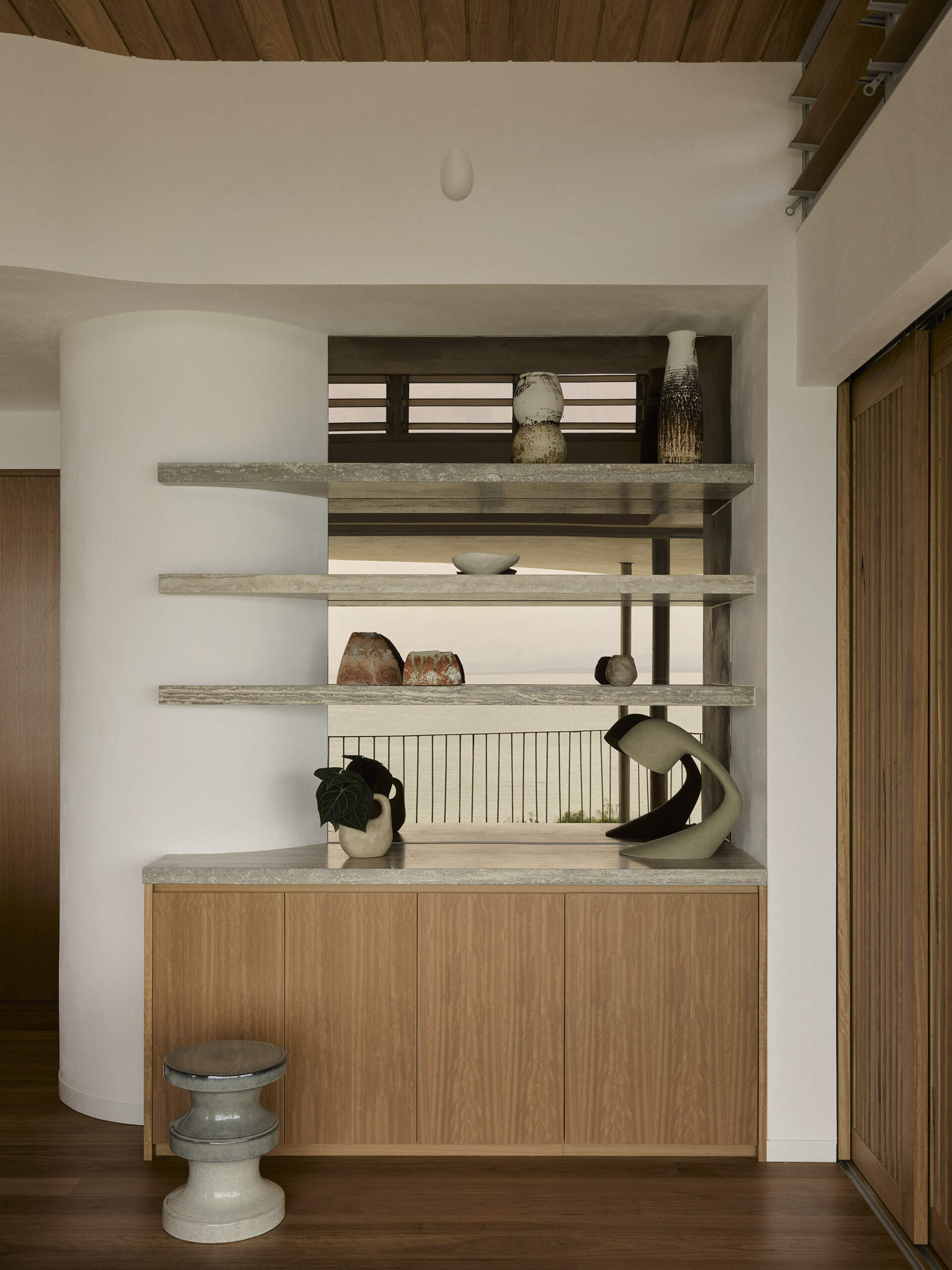 Explore the elevated primary bedroom of this Byron Bay home, featuring warm timber, earthy finishes, mirrored surfaces and large openings that frame the expansive coastal outlook.