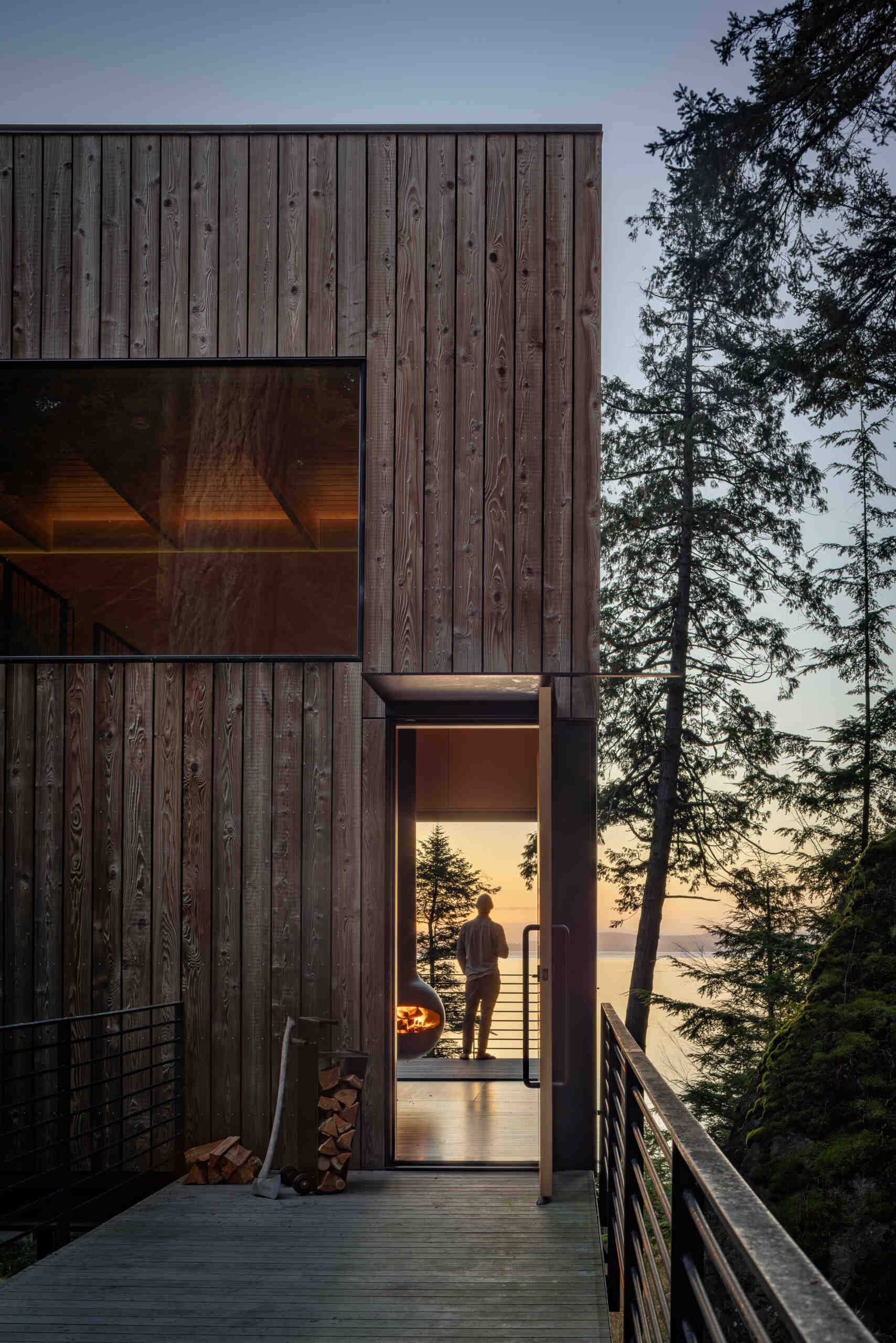 A suspended metal walkway winds through the forest to this tiny Blakely Island cabin, revealing views of Thatcher Bay before reaching the fir entry door.
