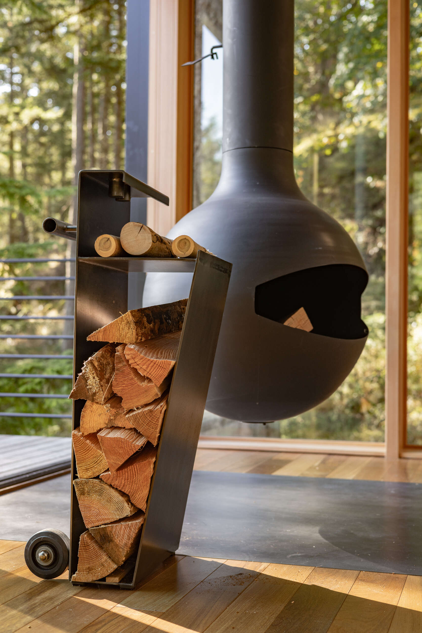 A custom steel fire cart and fireplace tools fit neatly into an angled storage nook in this 400-square-foot Blakely Island cabin by Wittman Estes.