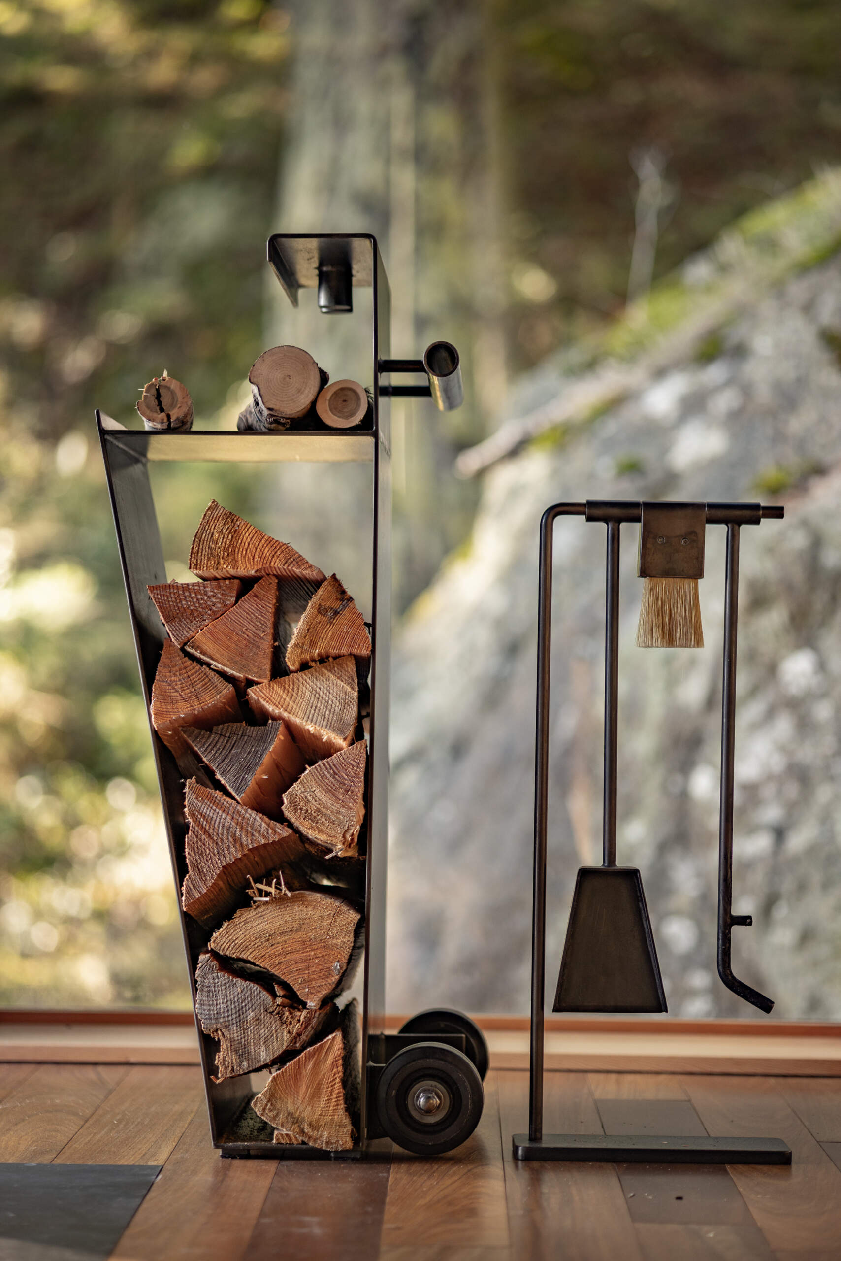 A custom steel fire cart and fireplace tools fit neatly into an angled storage nook in this 400-square-foot Blakely Island cabin by Wittman Estes.